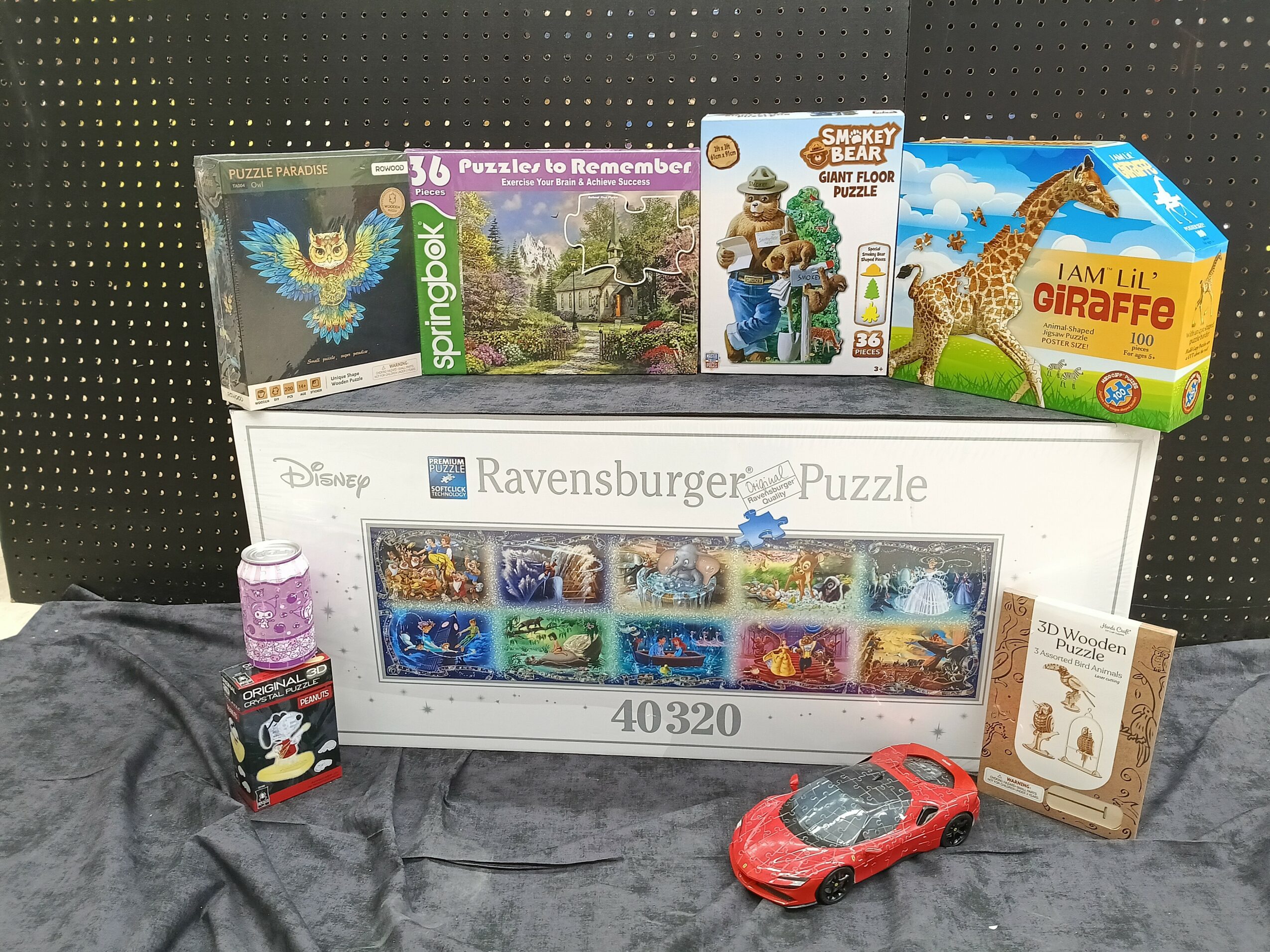 Collection of children's toys, puzzles, and a red toy car on a gray surface with a black background.