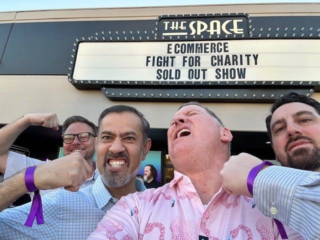 Group of people smiling and laughing in front of a marquee sign at a theater.