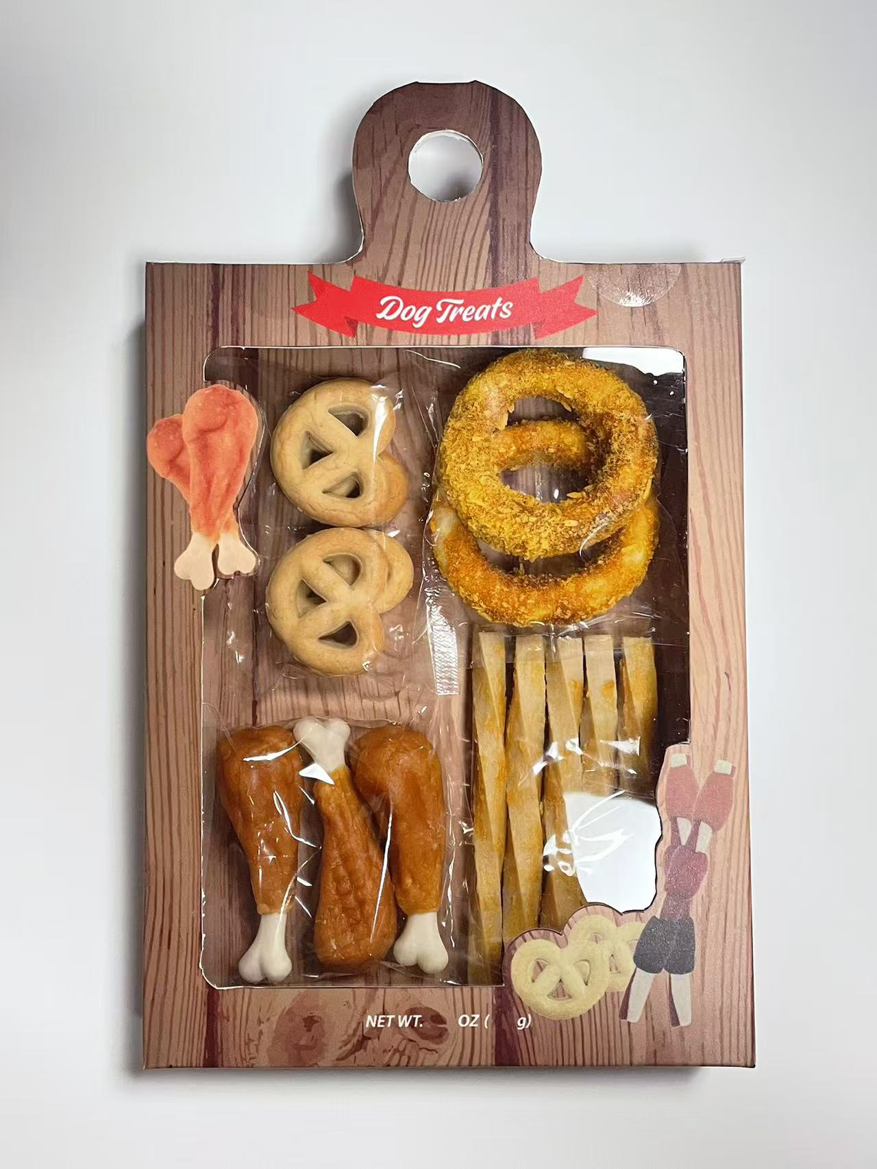 Dog treat shaped like a chicken leg, pretzels, onion rings, chicken drumsticks, and a bone-shaped treat on a wooden board.