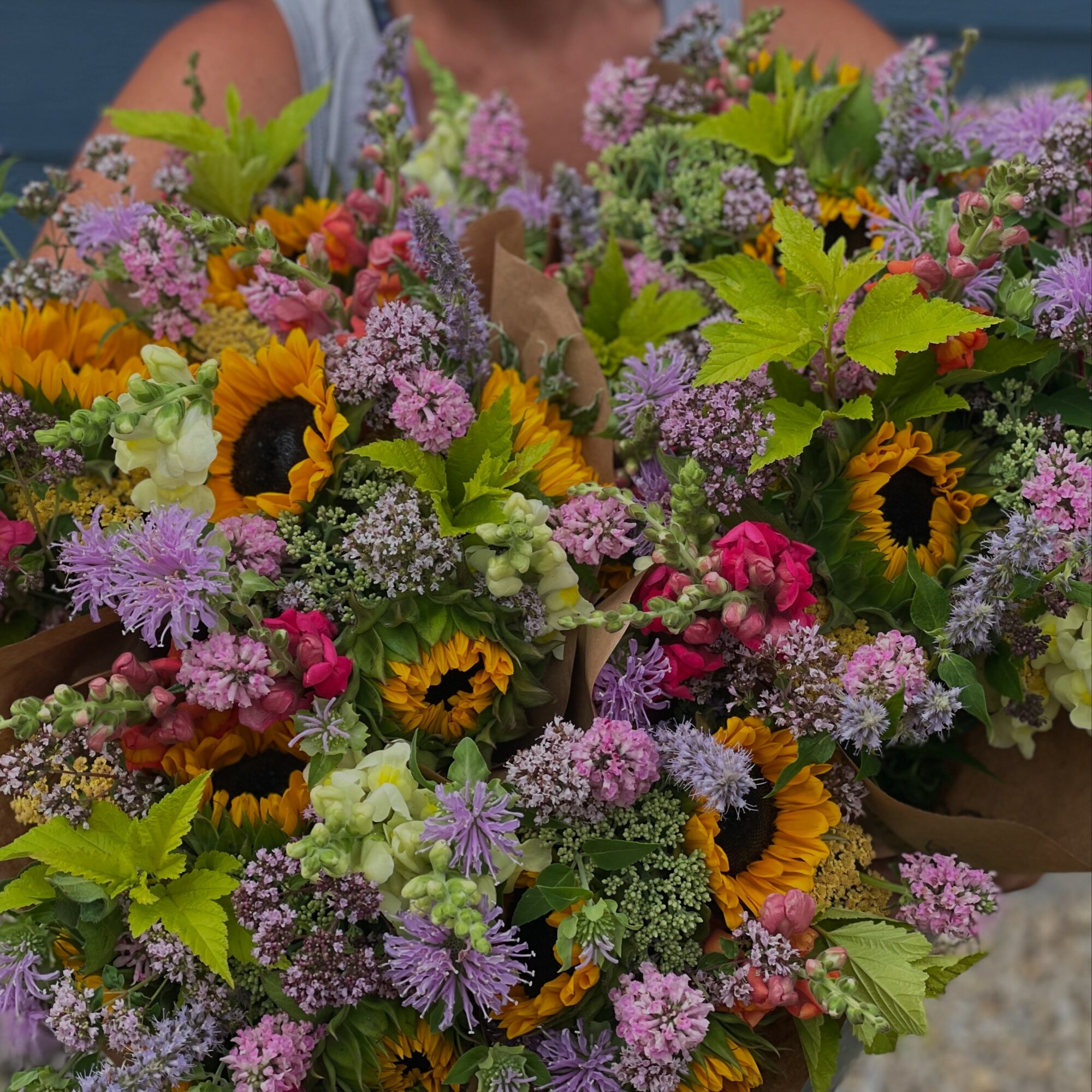 Two large bouquets of colorful flowers including sunflowers, pink, purple, and white blossoms with green leaves.
