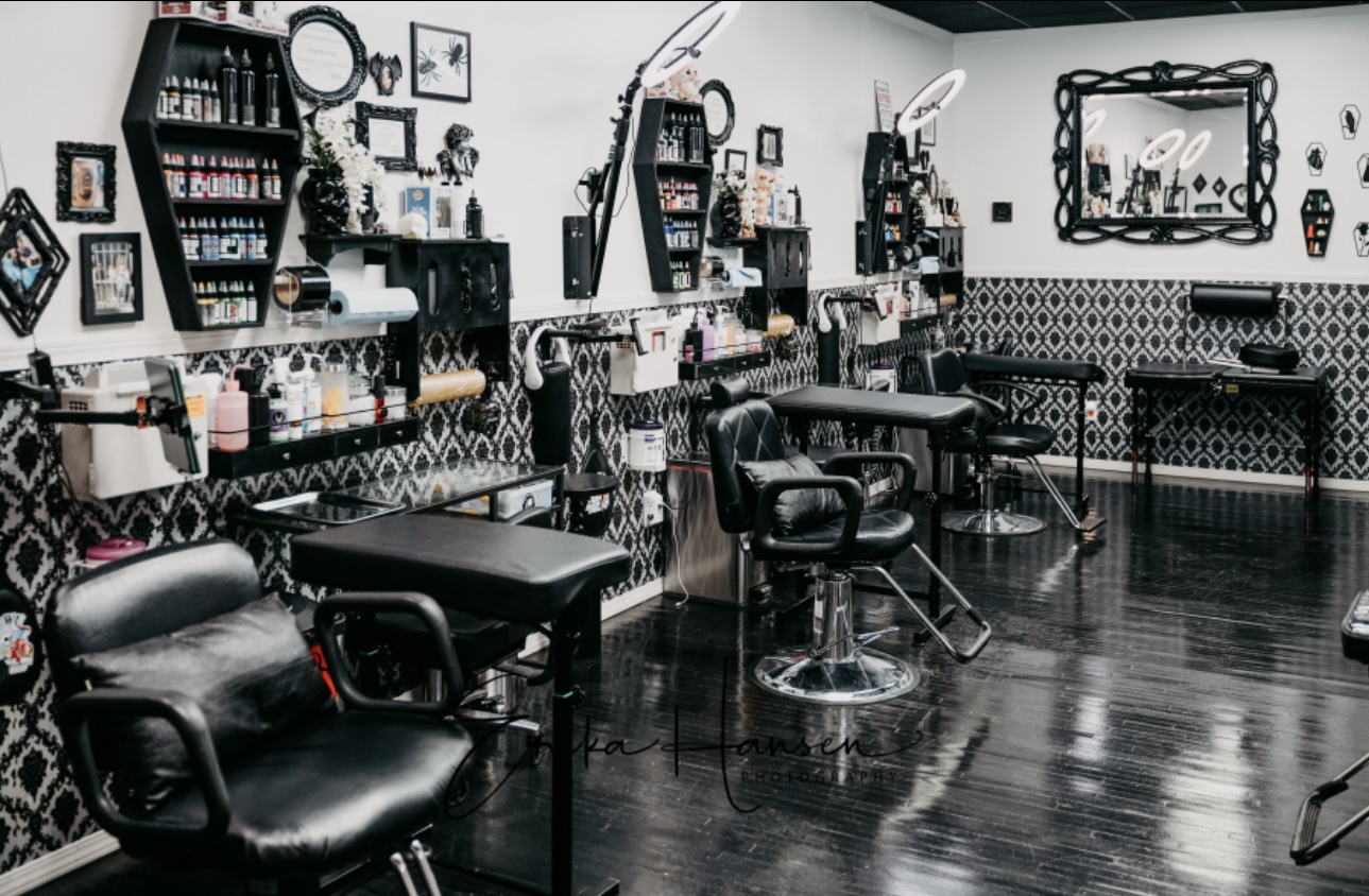 Empty hair salon with chairs, mirrors, and shelves on black and white patterned walls.