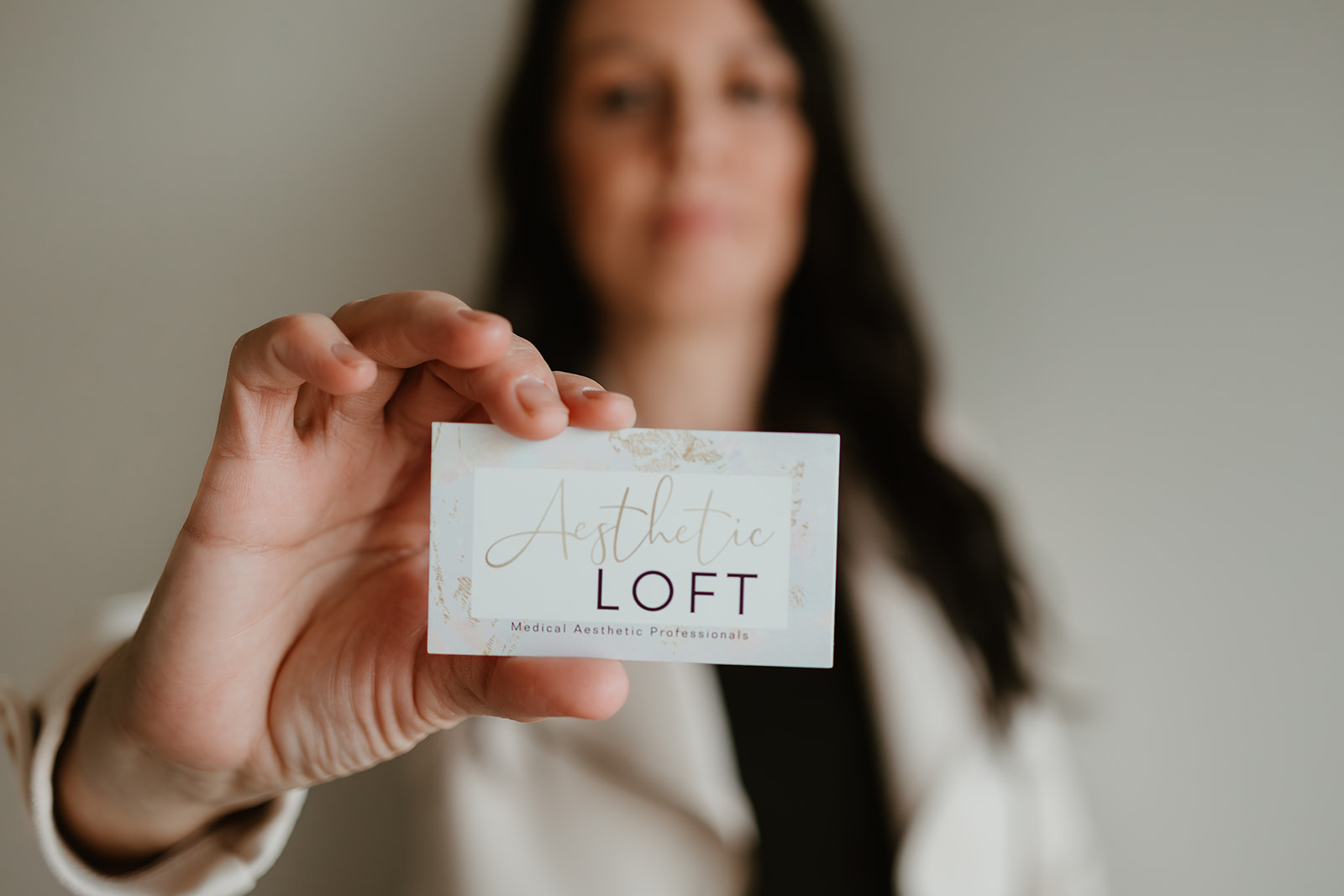 Person holding a card with the text 'Athletic LOFT' visible, blurred background, focus on hand and card.