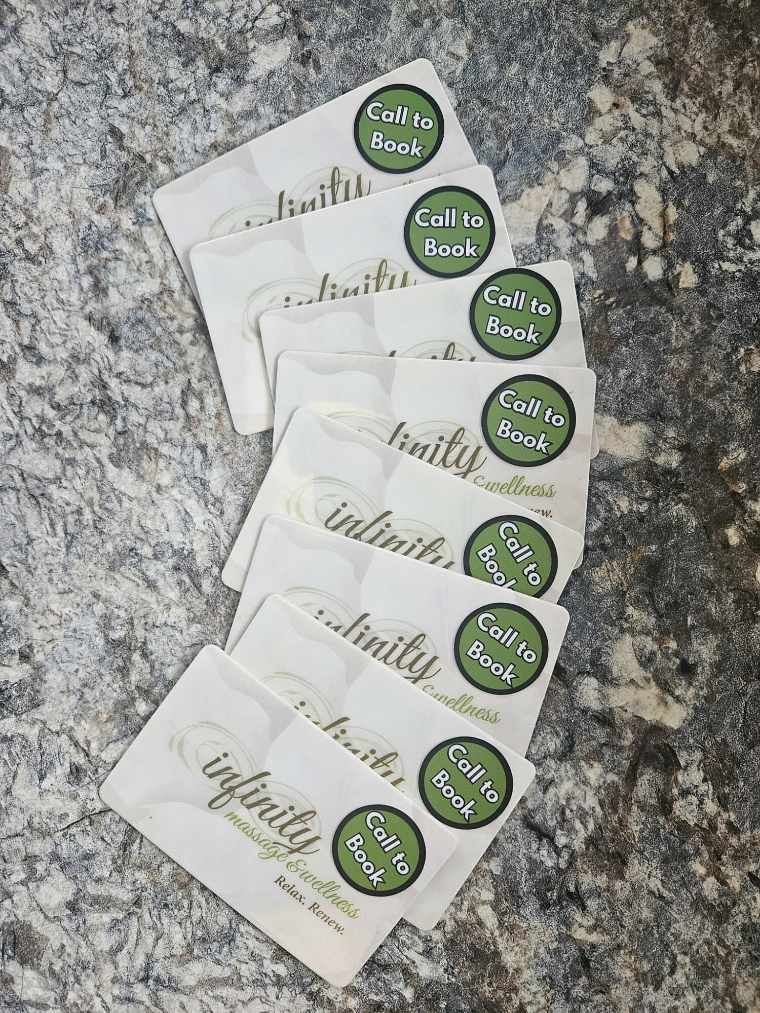 Stack of five white cards with green circular stickers reading 'Call to Book' on a textured surface.