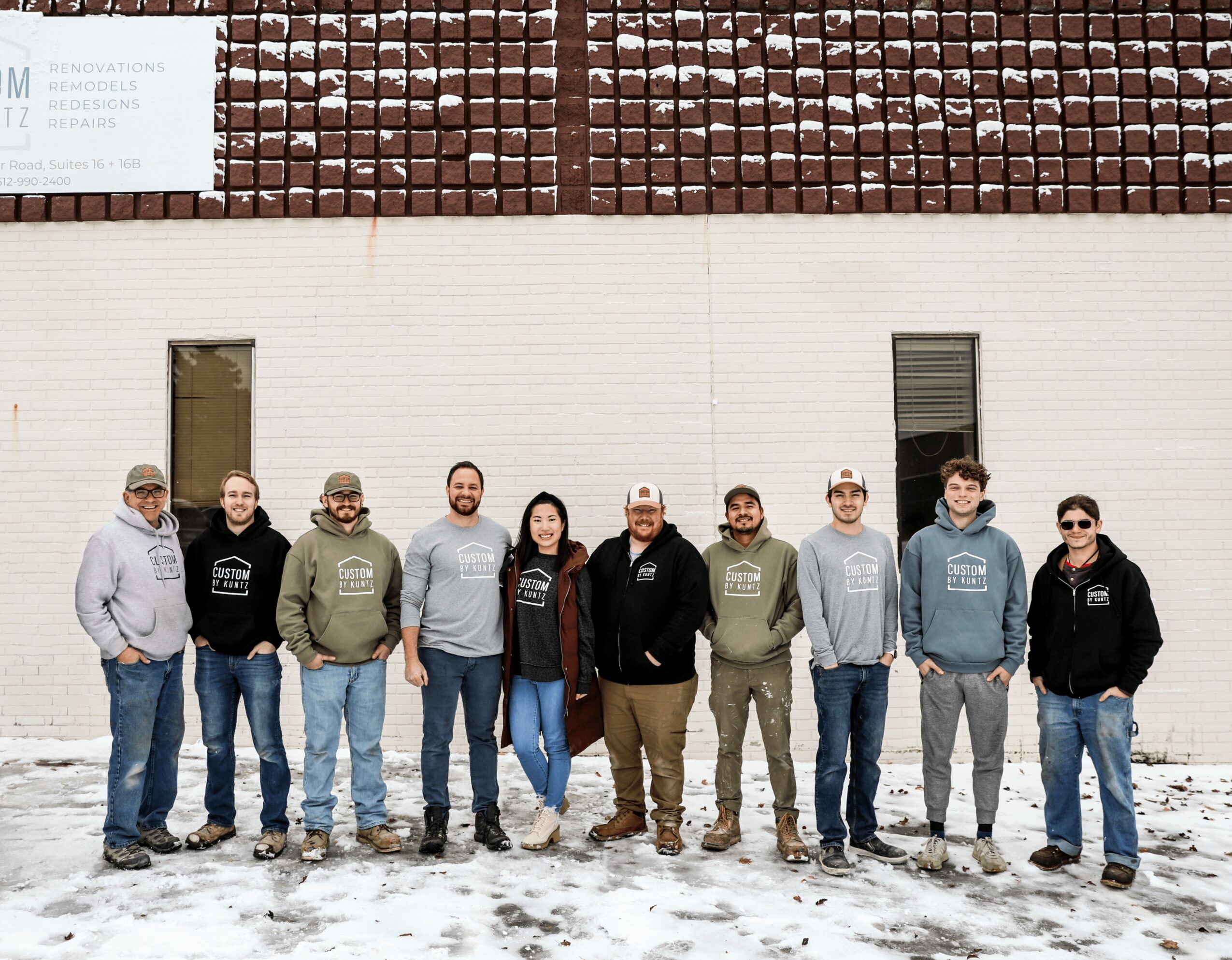 Group of ten people standing outdoors in front of a building with snow on the ground.