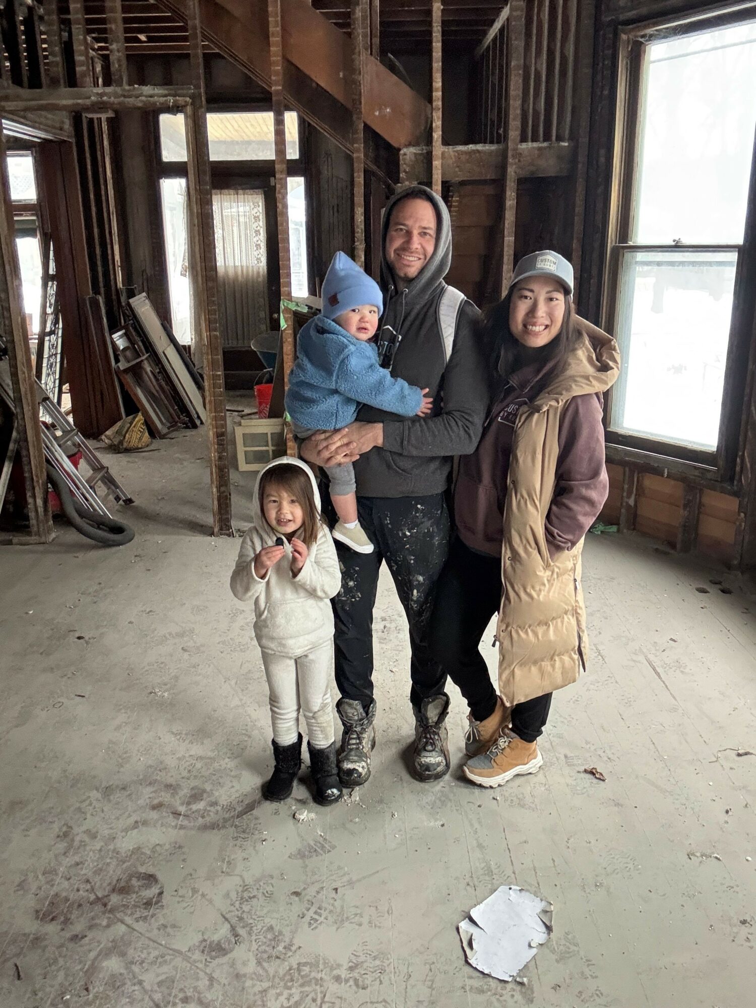 Family of four standing inside a rustic wooden building, with two children and two adults smiling at the camera.
