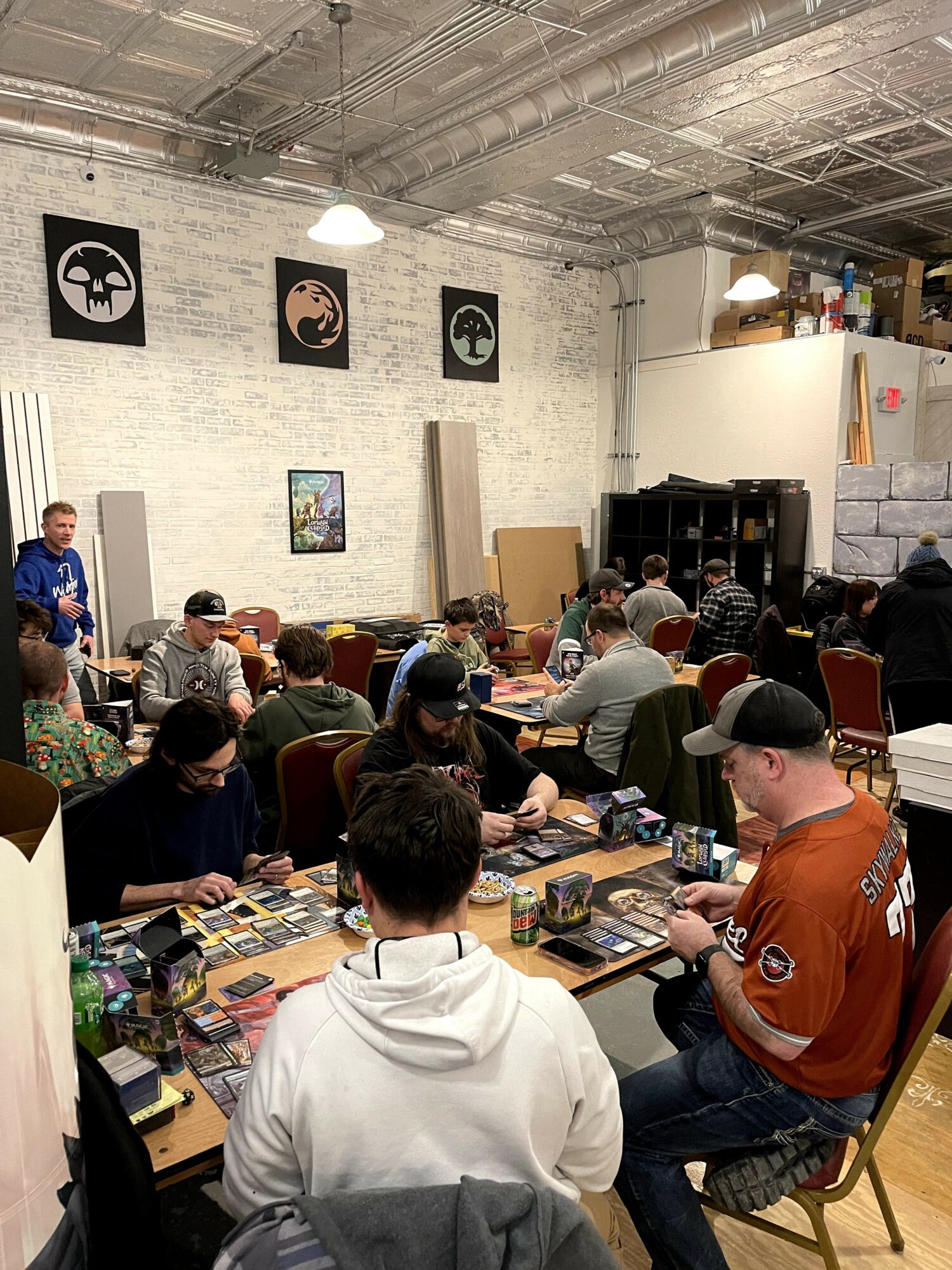 Group of people seated at tables in a room with white brick walls and artwork, participating in an event or workshop.