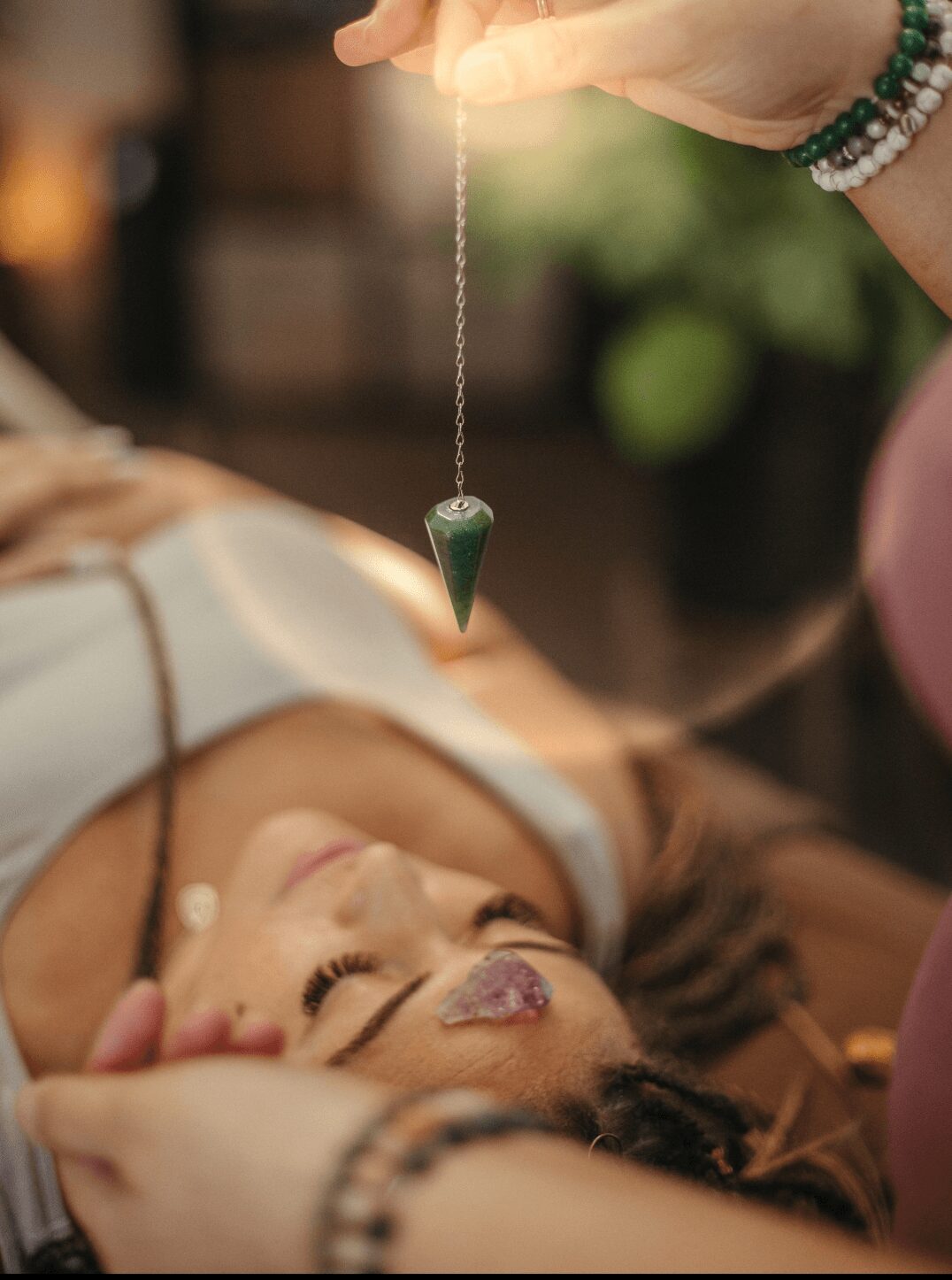 Person lying down with eyes closed, receiving a facial treatment, with a jade roller near face, in a spa setting.