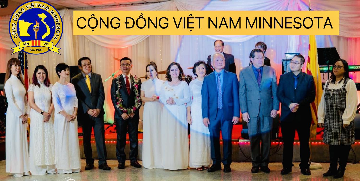 Group of people standing on stage with a banner reading 'Vietnamese Community Minnesota' in Vietnamese.