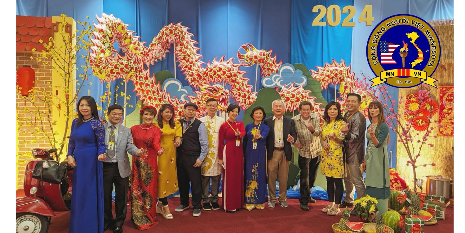 Group of people standing on stage with dragon decorations, celebrating 2024, with a logo and colorful background.