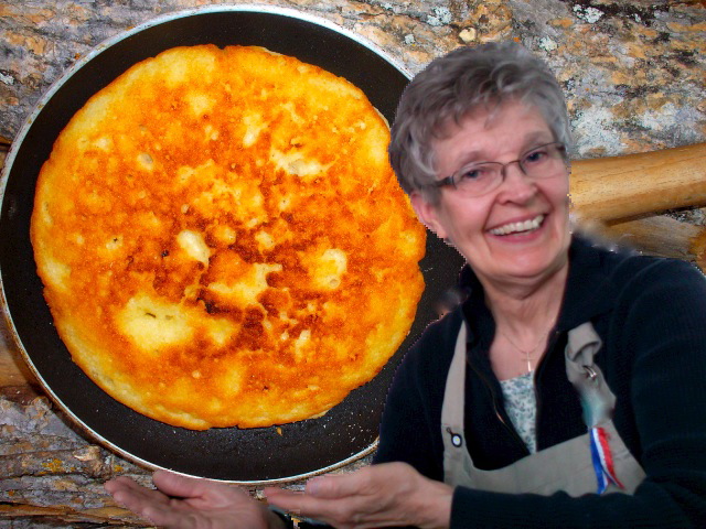 Woman smiling holding a frying pan with a cooked dish, kitchen background.