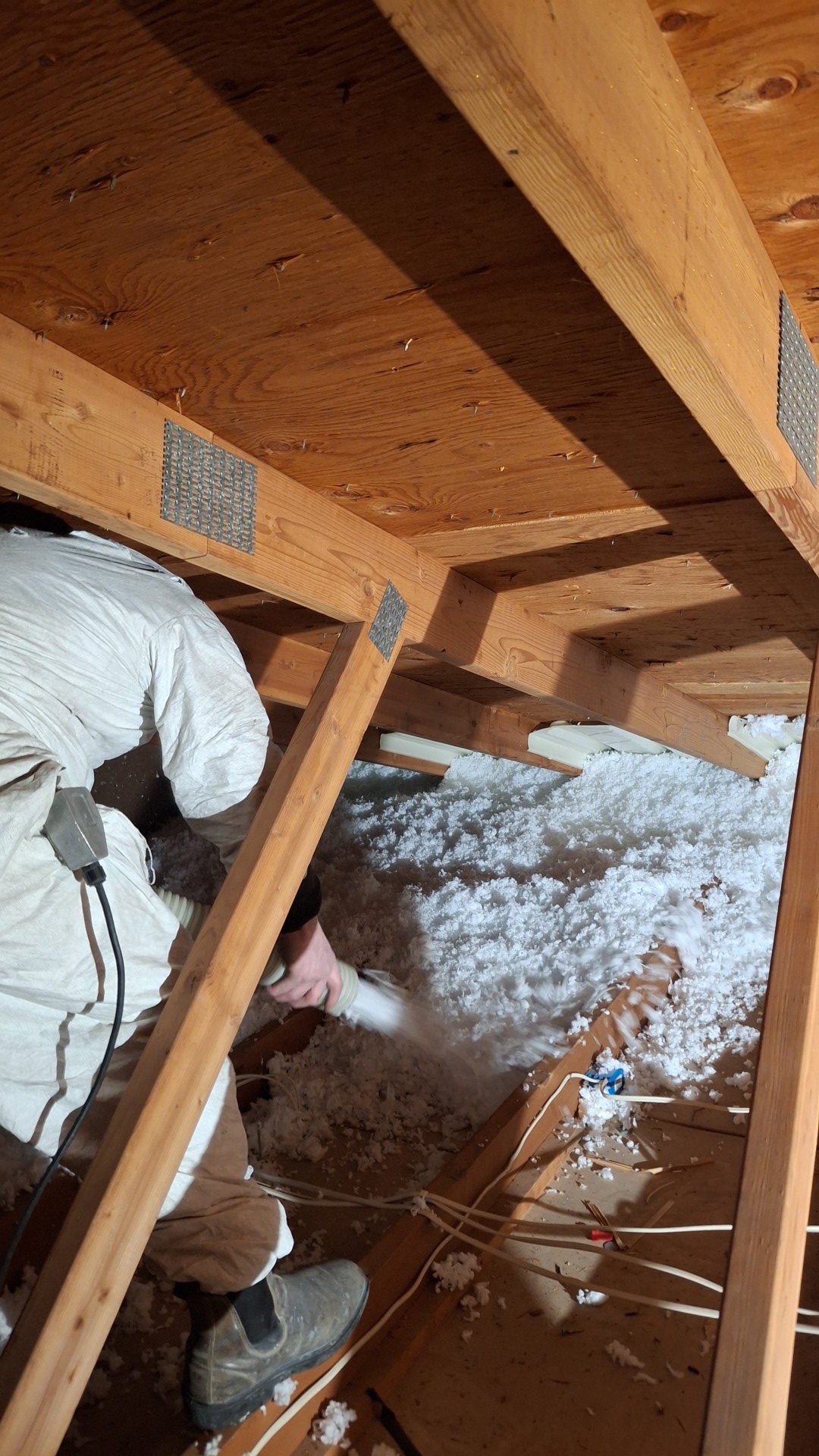 Person working under a wooden structure with snow on the ground outside.
