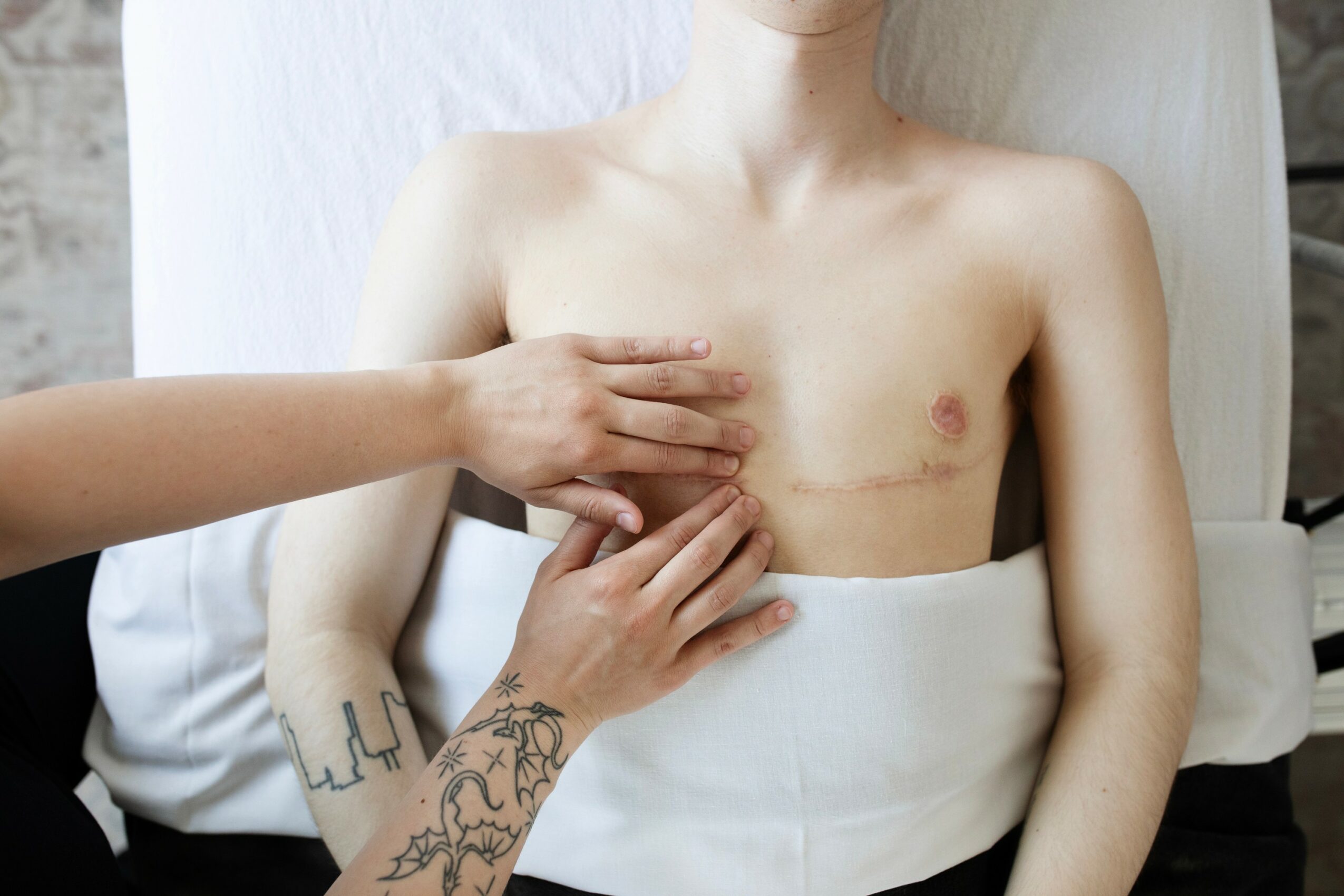Person receiving a medical examination, with hands on their chest, in a clinical setting.