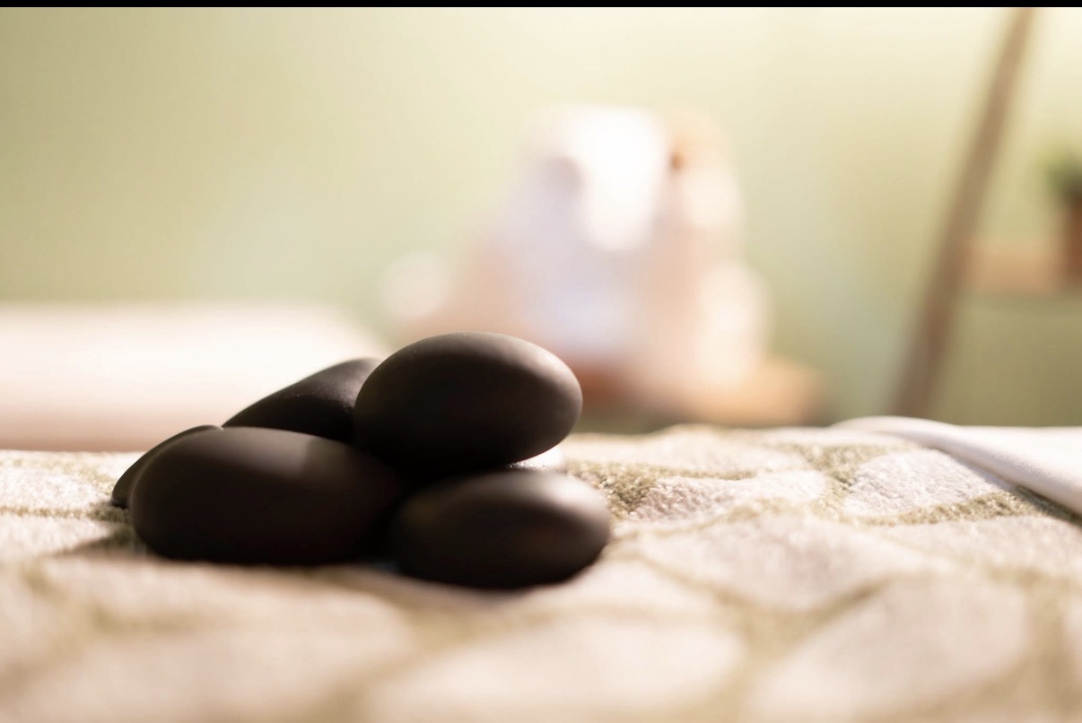 Three smooth black stones on a textured surface with a blurred background.