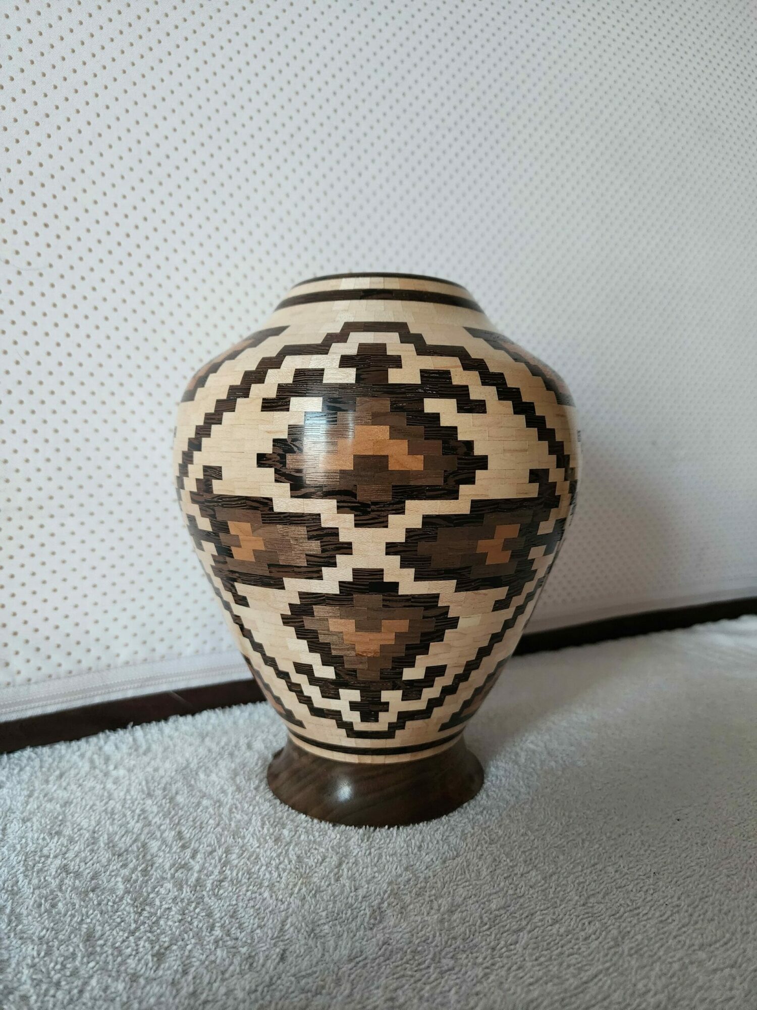 Decorative vase with geometric patterns on a surface, viewed from the side.