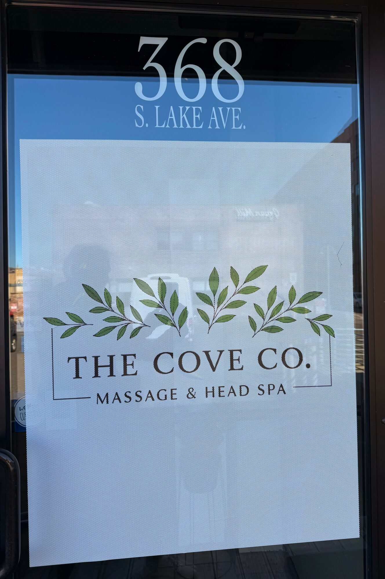 Sign displaying address 368 S. Lake Ave. and logo for The Cove Co. Massage & Head Spa with green leaves.