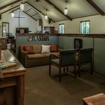 Interior of a cozy room with a sofa, chairs, and a sign that says 'PRAYER'.