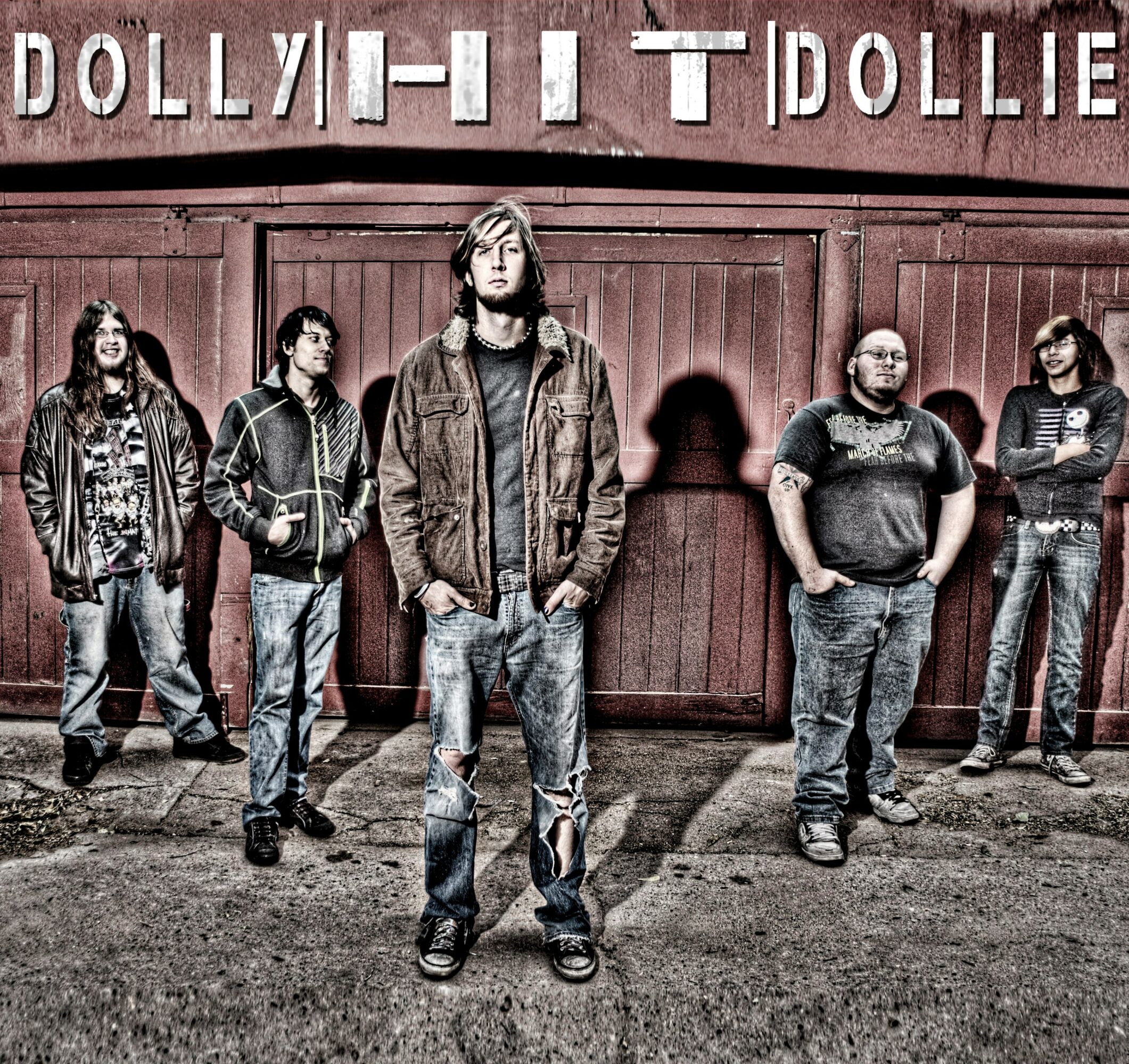 Group of five people standing in front of a wooden wall with a sign that reads 'DOLLY HIT DOLLIE'.