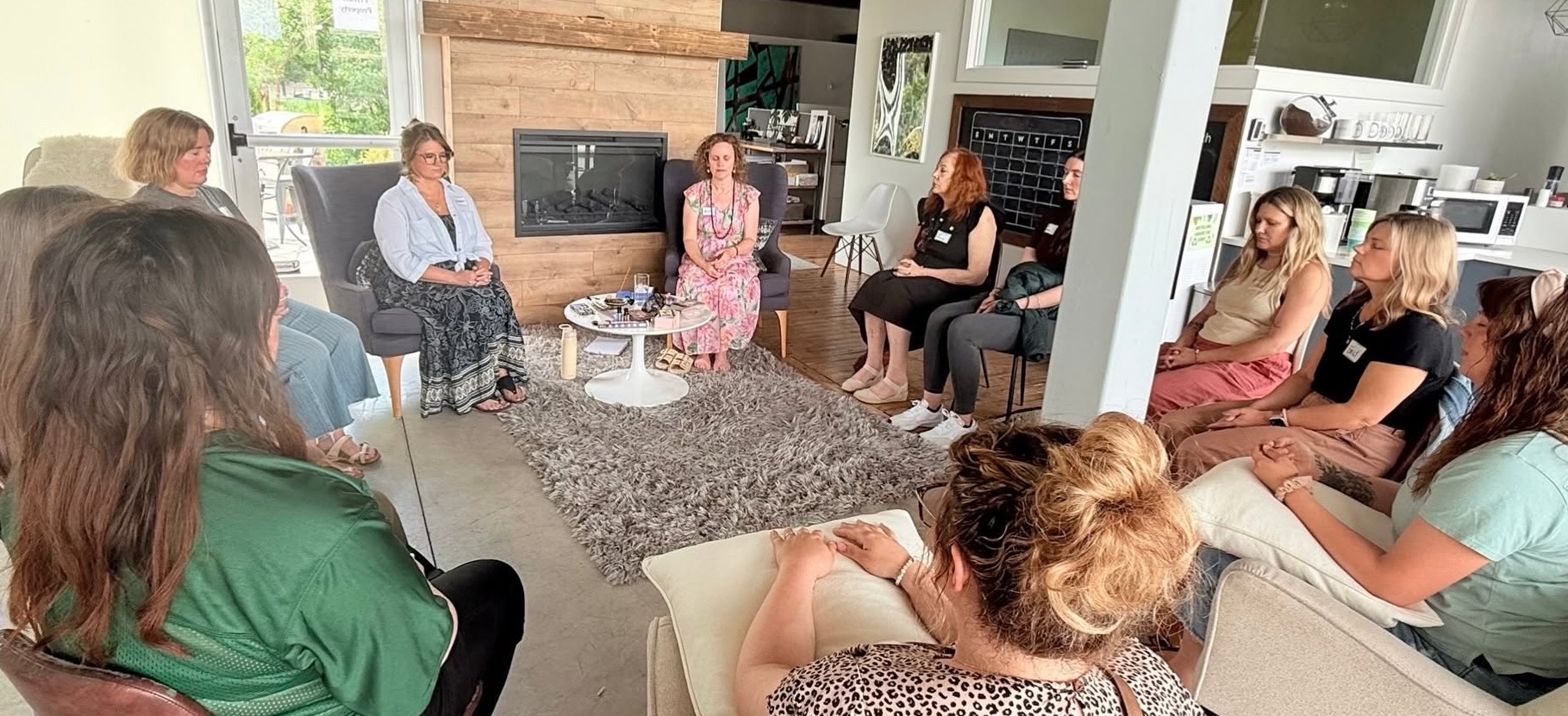 Group of people sitting in a circle in a bright room, engaging in a discussion or meeting.
