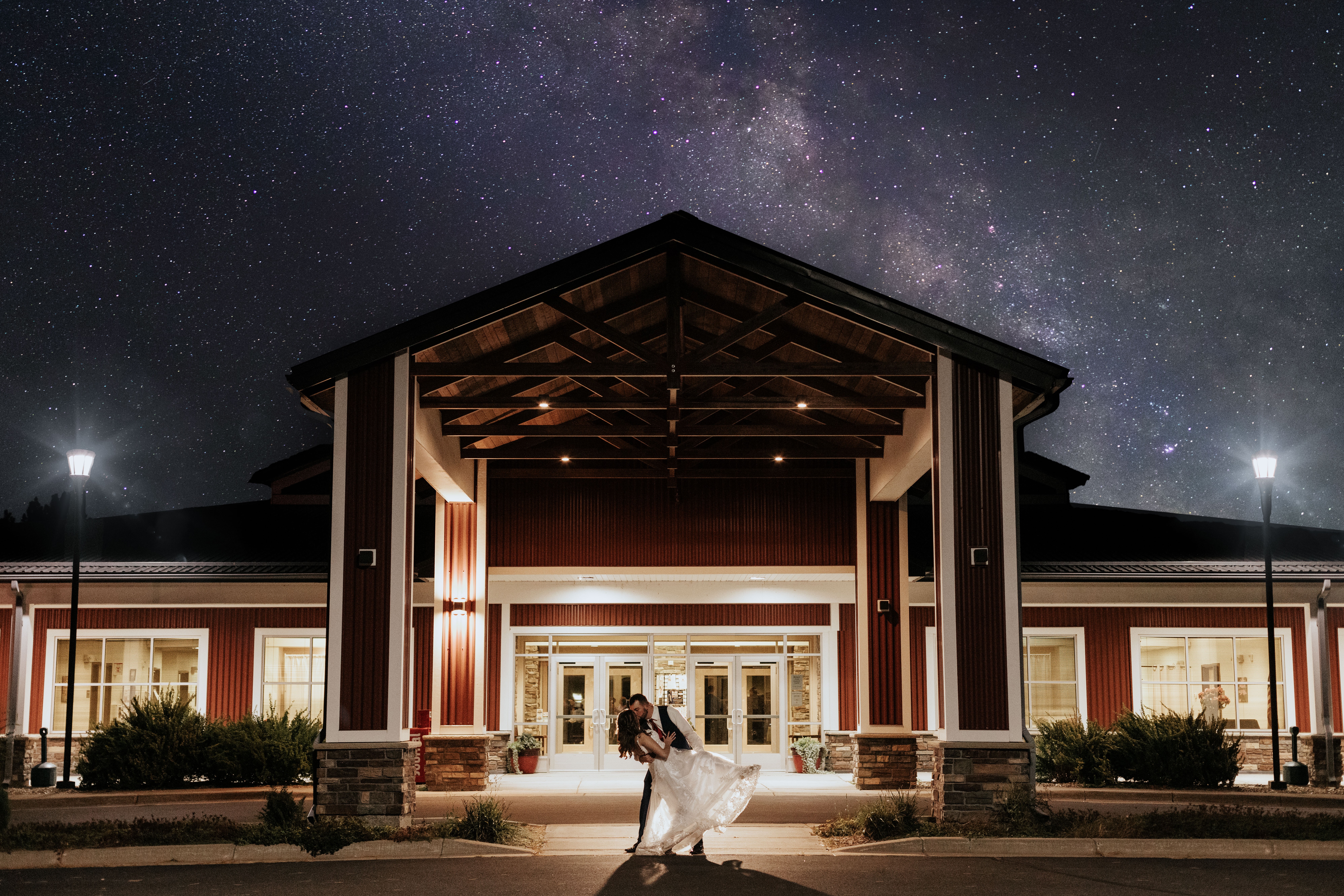 A person in a white dress stands in front of a building under a starry night sky.