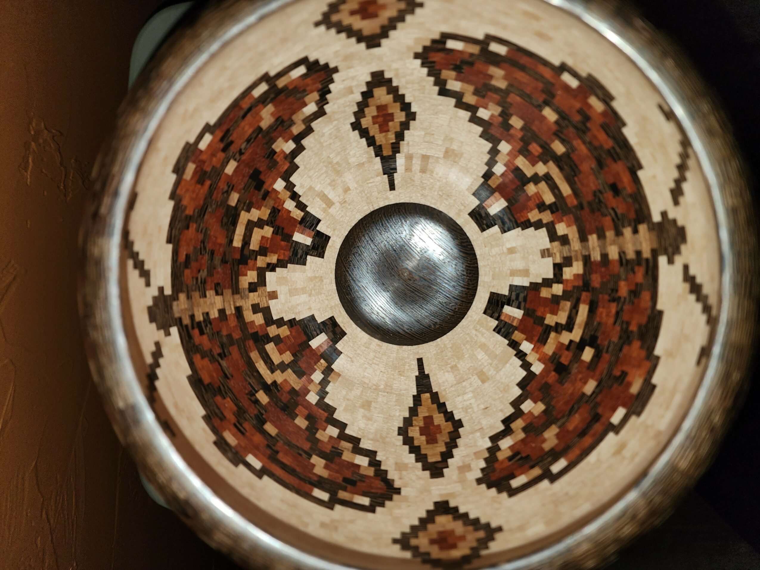 Close-up of a circular object with a detailed, symmetrical pattern in brown, beige, and black, and a metallic center.