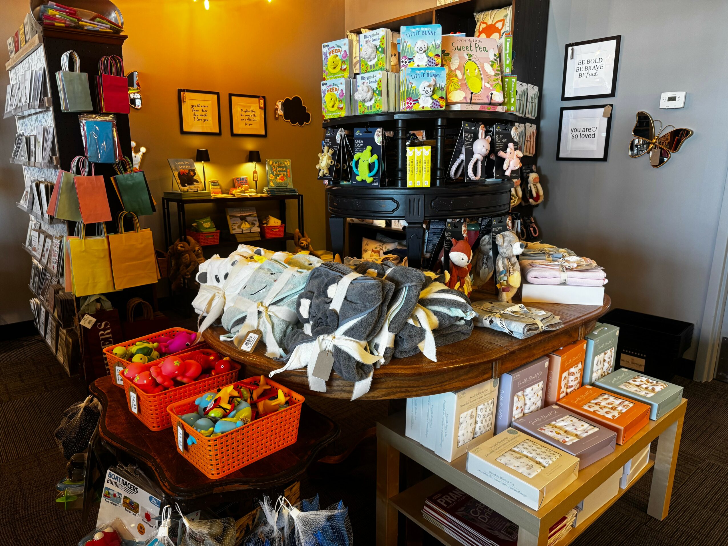 Display of children's toys, books, and clothing on a wooden table in a colorful store interior.