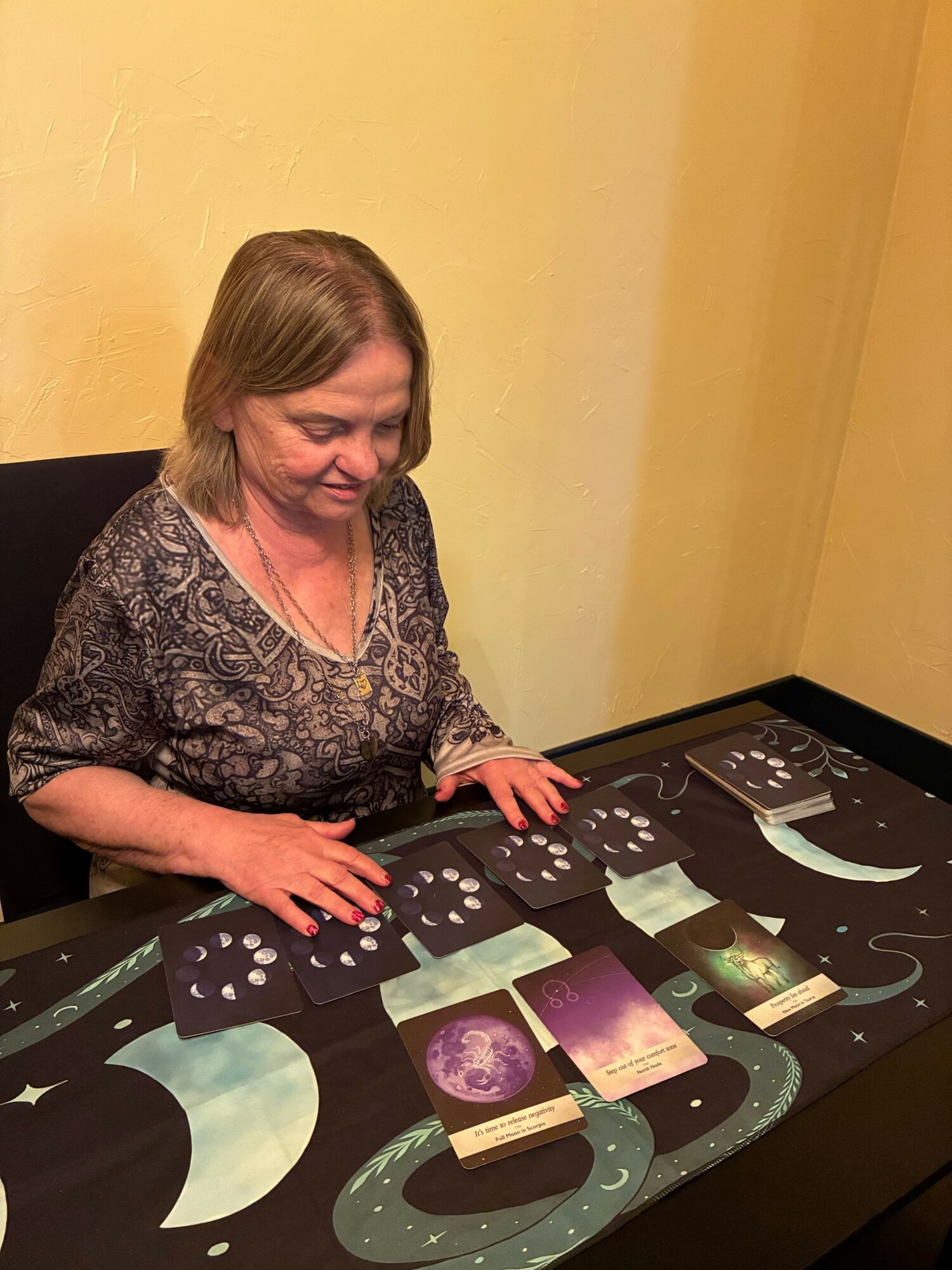 Woman playing a board game with dice and cards on a table, with a colorful game board in the background.