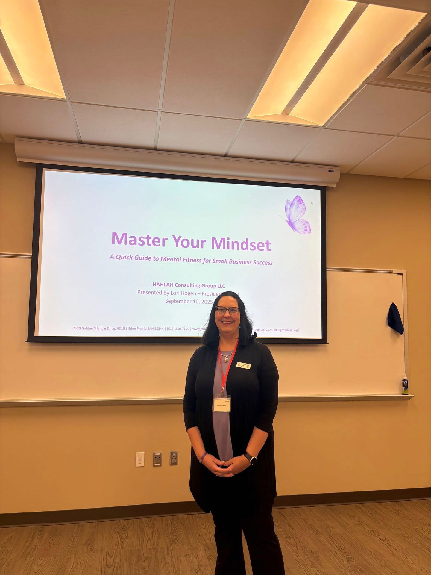 Woman standing in front of a presentation slide titled 'Master Your Mindset' in a classroom.