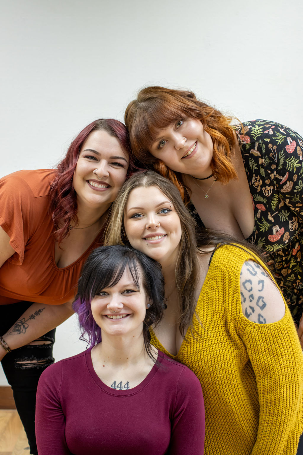 Four women smiling and posing together against a plain background.