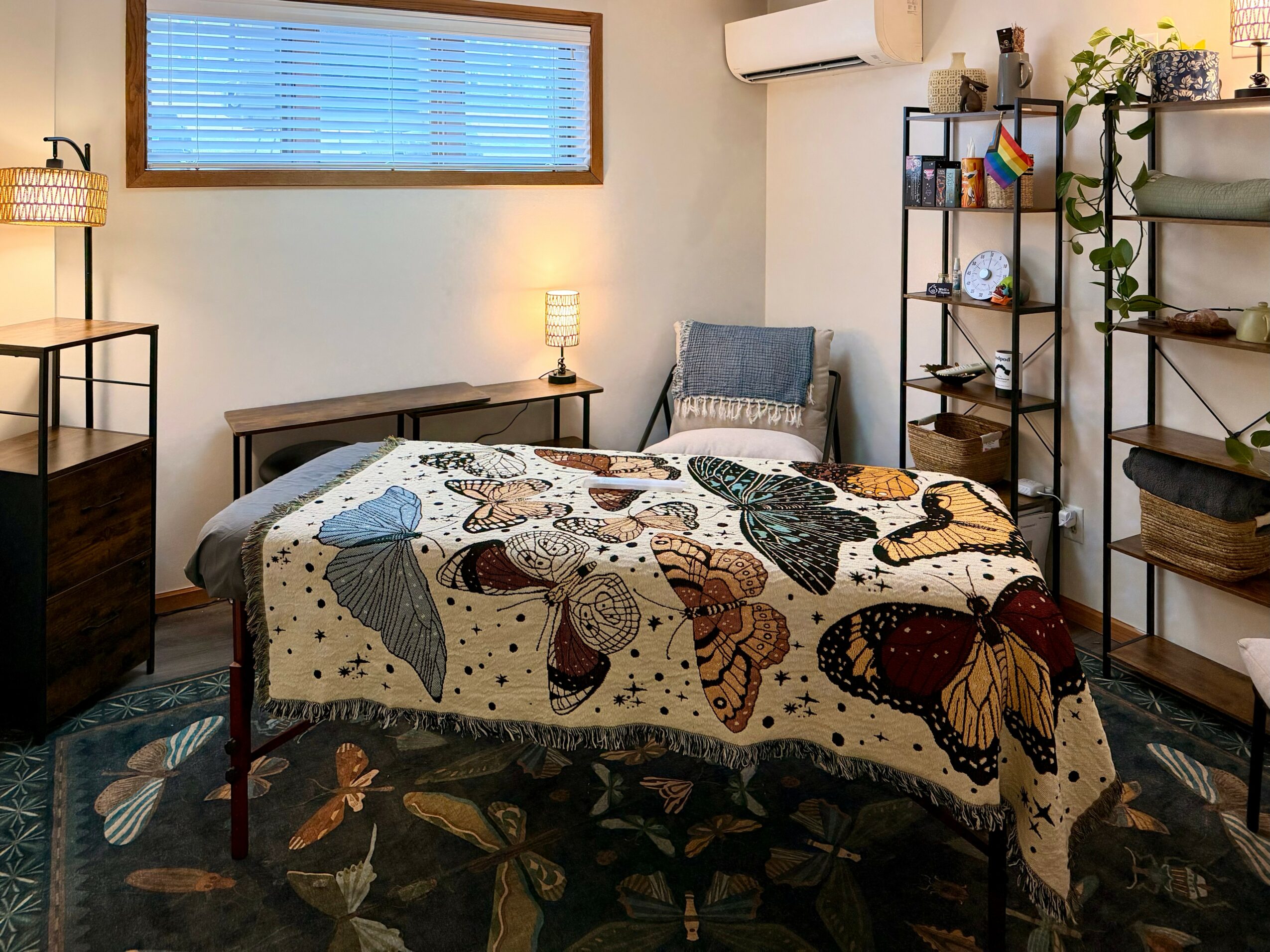 Bedroom with bed, side tables, shelves, and window, decorated with plants and a butterfly quilt, in neutral tones.