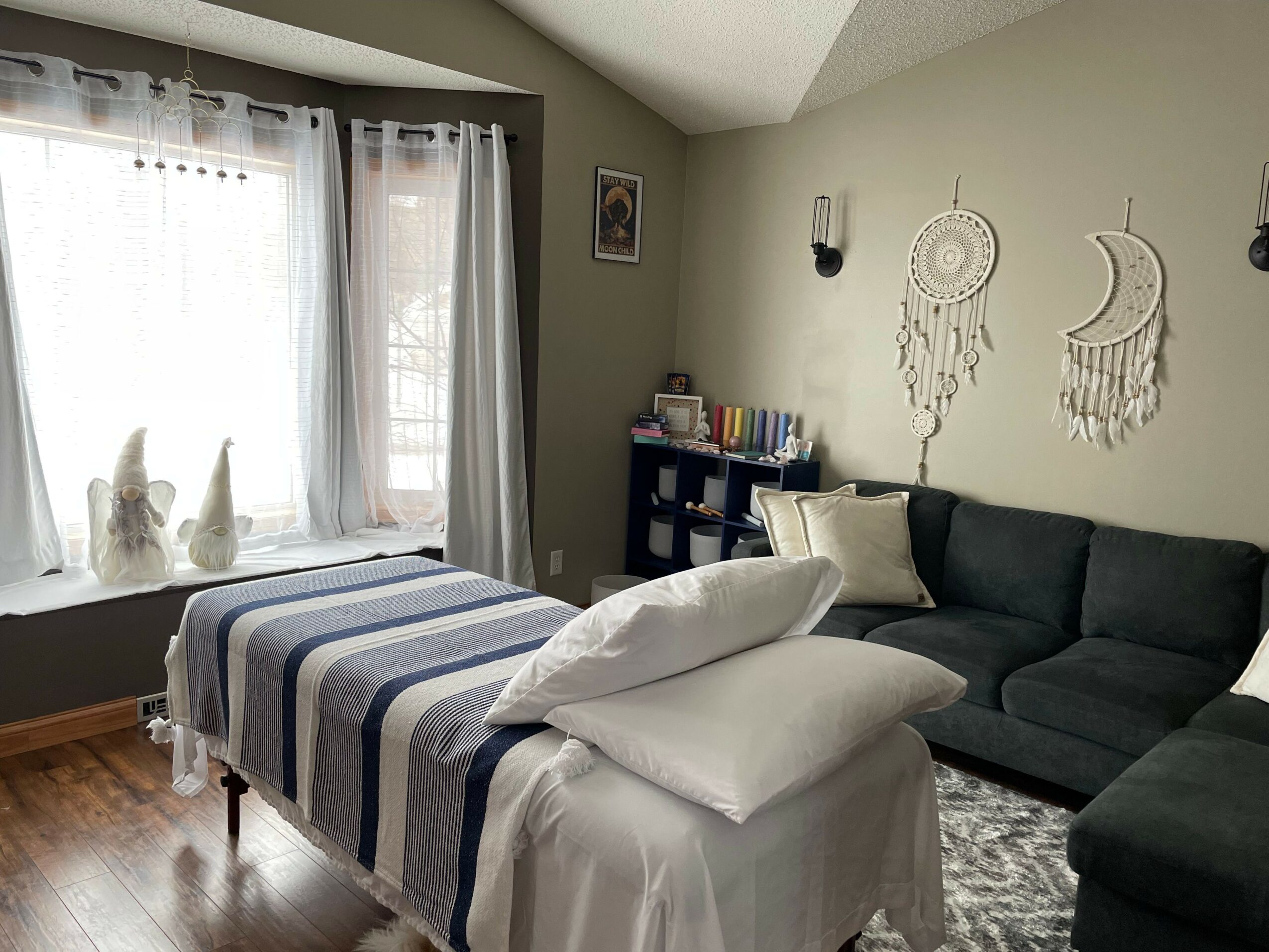 Living room with a bed, sofa, wall decorations, and a window with curtains.