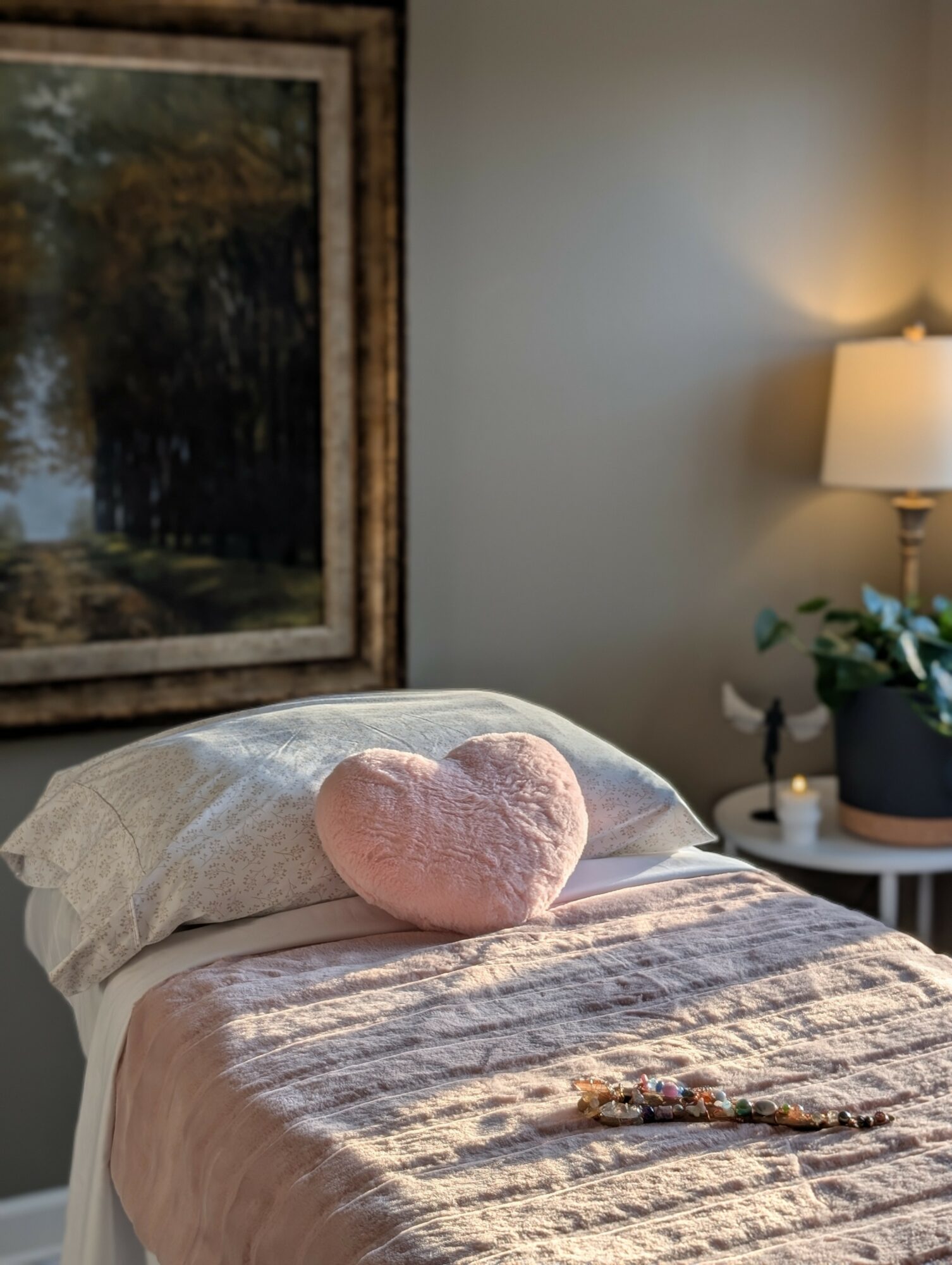 A bedroom with a bed, pink heart-shaped pillow, and sunlight casting shadows on the bedspread.