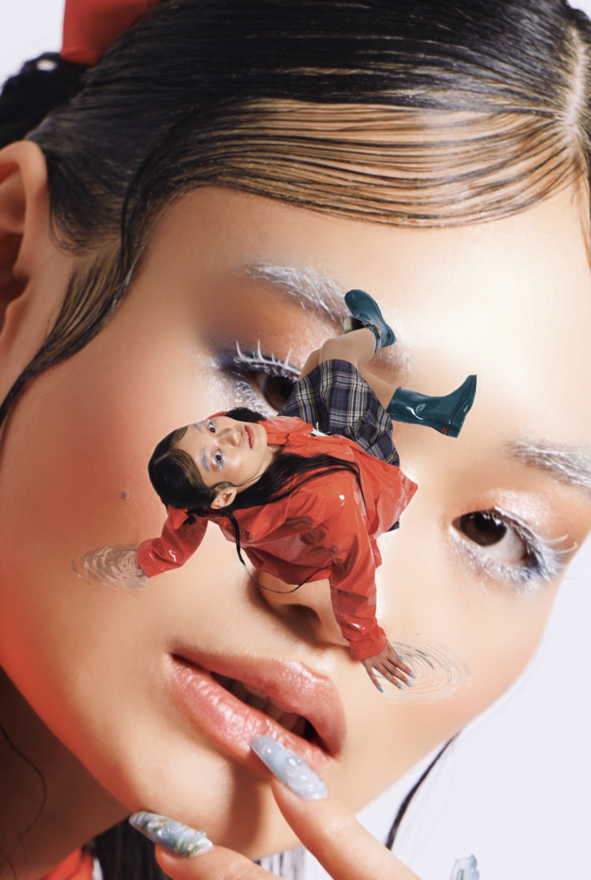 A woman with makeup and a small person in a red outfit lying on her face, holding her lips, against a white background.