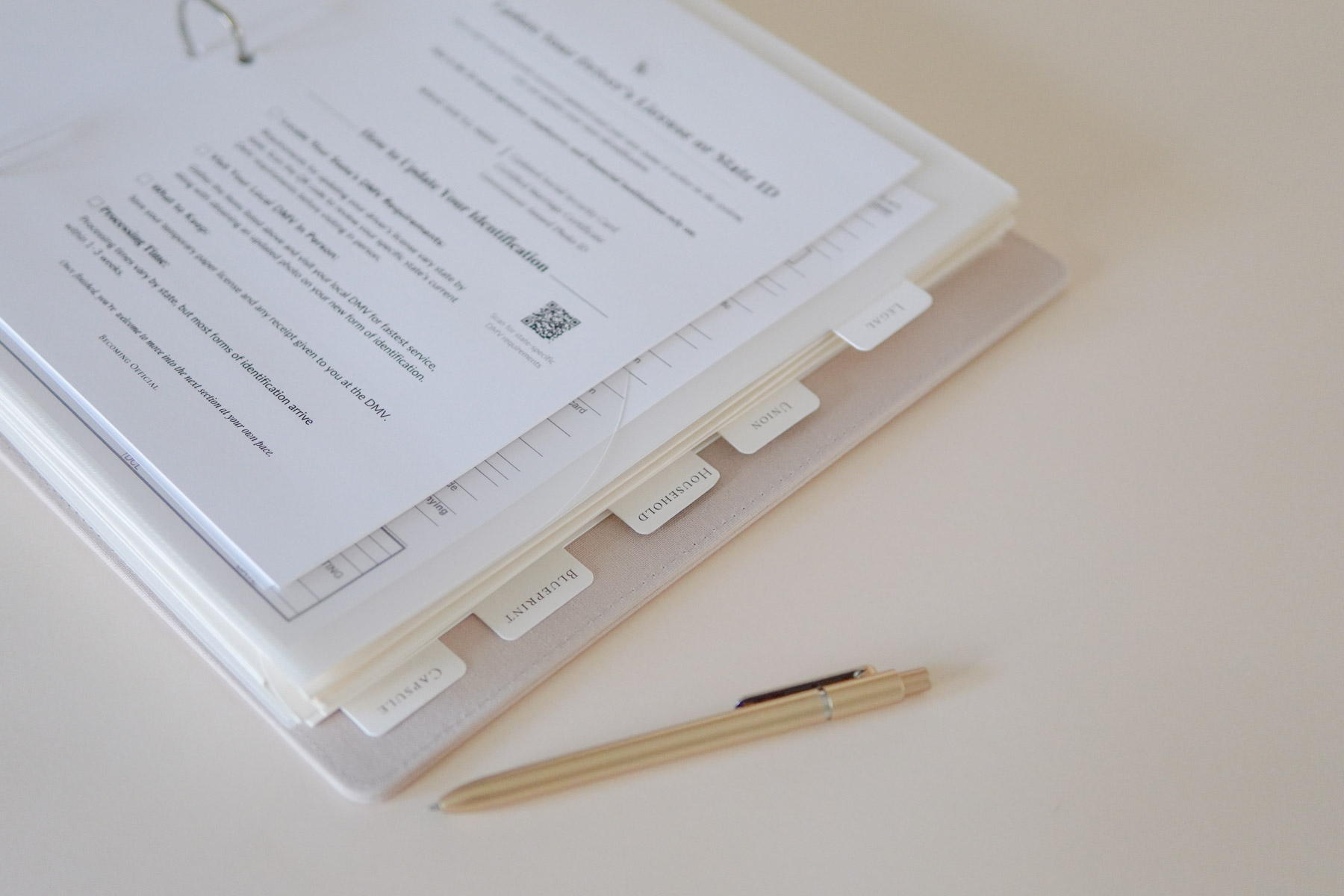 Stack of papers with tabs and a pen on a light-colored surface.