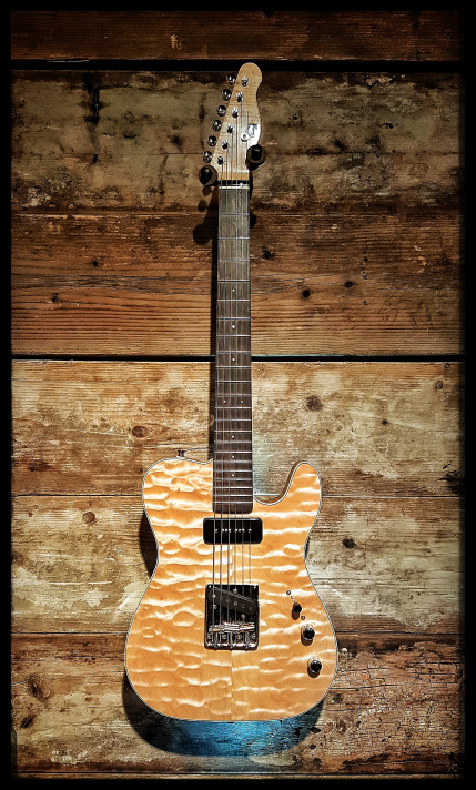 Electric guitar with a tiger stripe pattern, mounted on a wooden wall background.