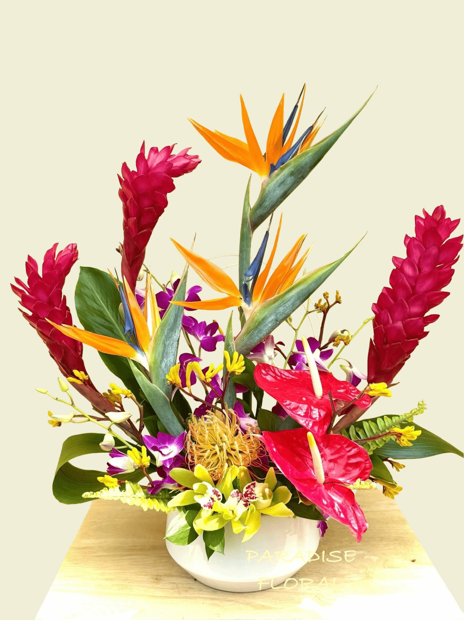 Colorful flower arrangement with orange, pink, purple, and yellow flowers in a white vase on a light background.