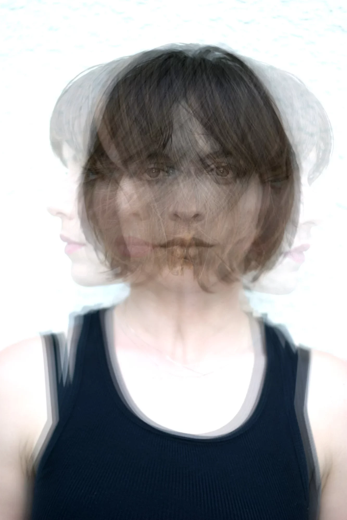 A person with short dark hair wearing a dark sleeveless top, multiple overlapping images create a blurred effect.