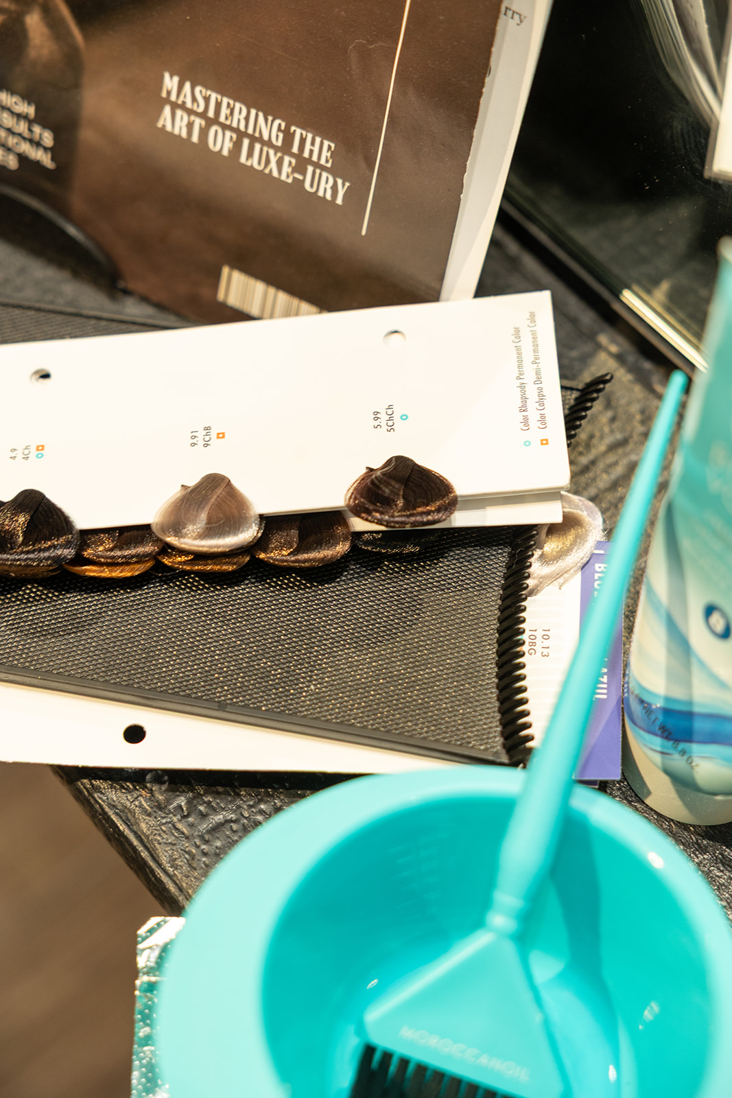 A row of chocolates on a white strip, a tablet, a black notebook, a blue cup with a straw, and a water bottle.