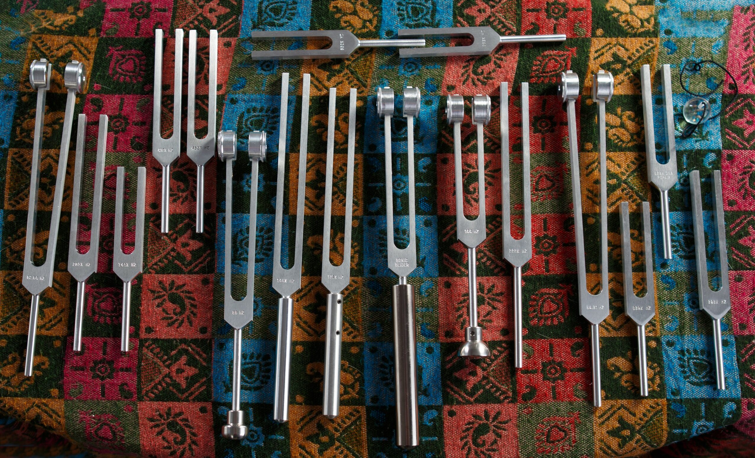 Collection of metal tools with various shapes and sizes on a colorful patterned fabric background.