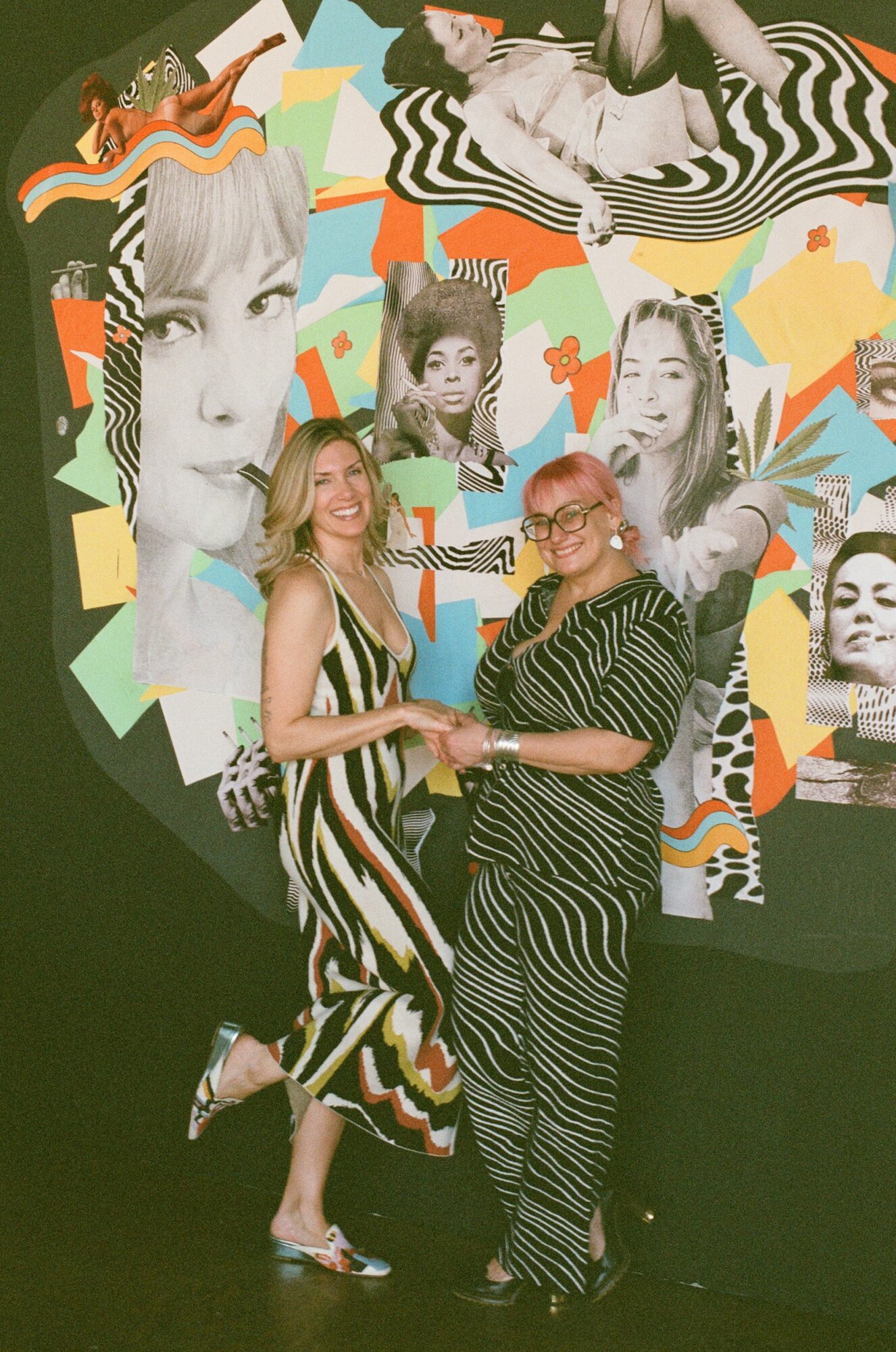 Two women shake hands in front of a colorful collage of black-and-white portraits and abstract shapes.