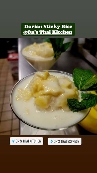 Two glasses of durian sticky rice dessert topped with durian pieces and mint leaves, on a dark surface.