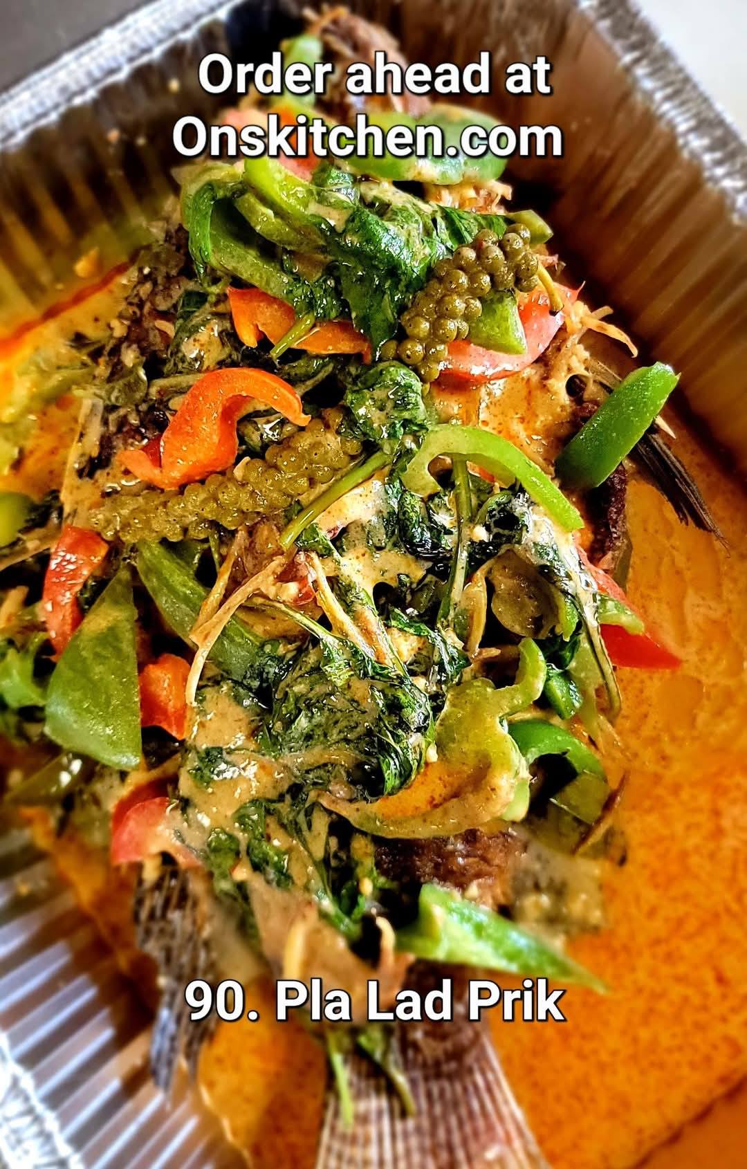 Mixed vegetable dish with greens, carrots, and herbs in a container, garnished with green chili and spices.