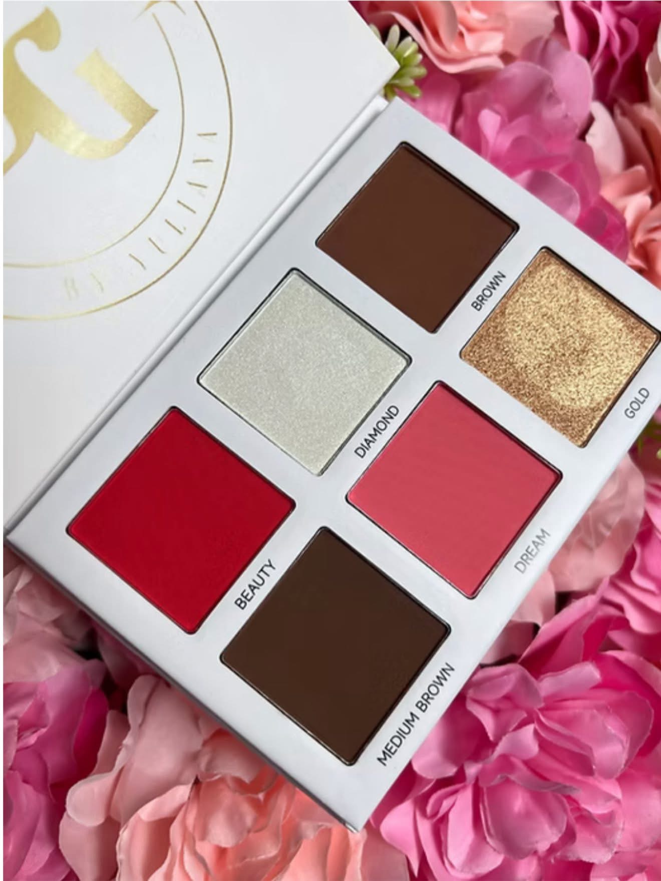 Open eyeshadow palette with six shades on pink flowers background, labeled Beauty, Medium Brown, Champagne, Dream, Gaze, and Shine.