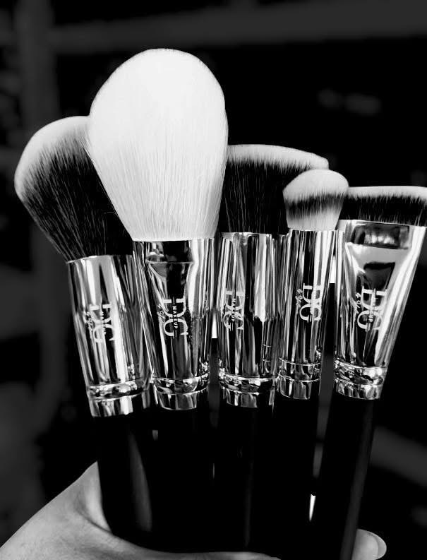 Collection of makeup brushes with various sizes and shapes, held together, in black and white.