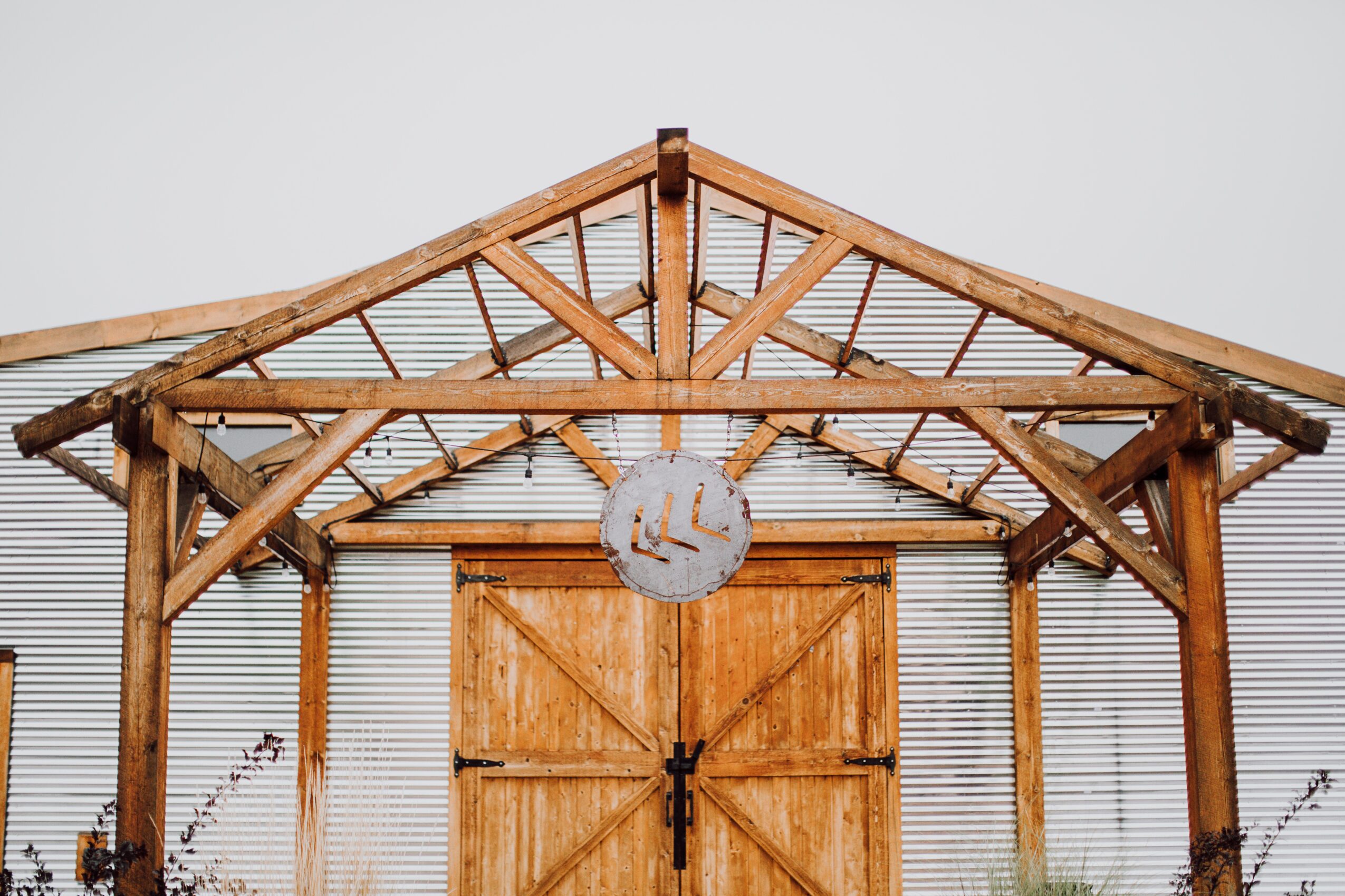 Wooden structure with a circular sign hanging in the center, metal siding background, and a simple roof design.