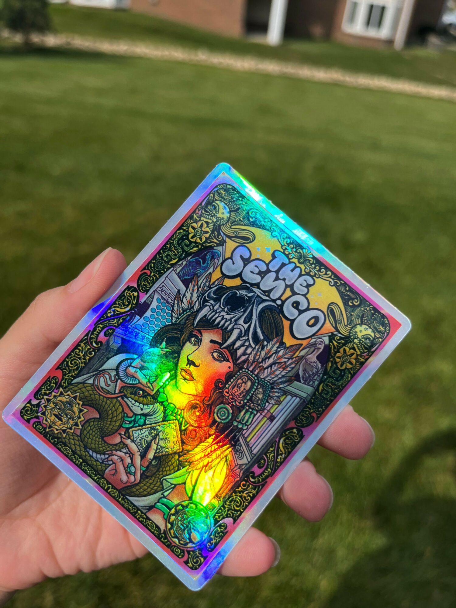 Hand holding a colorful, holographic card with a detailed illustration of a character with spiky hair and vibrant background.