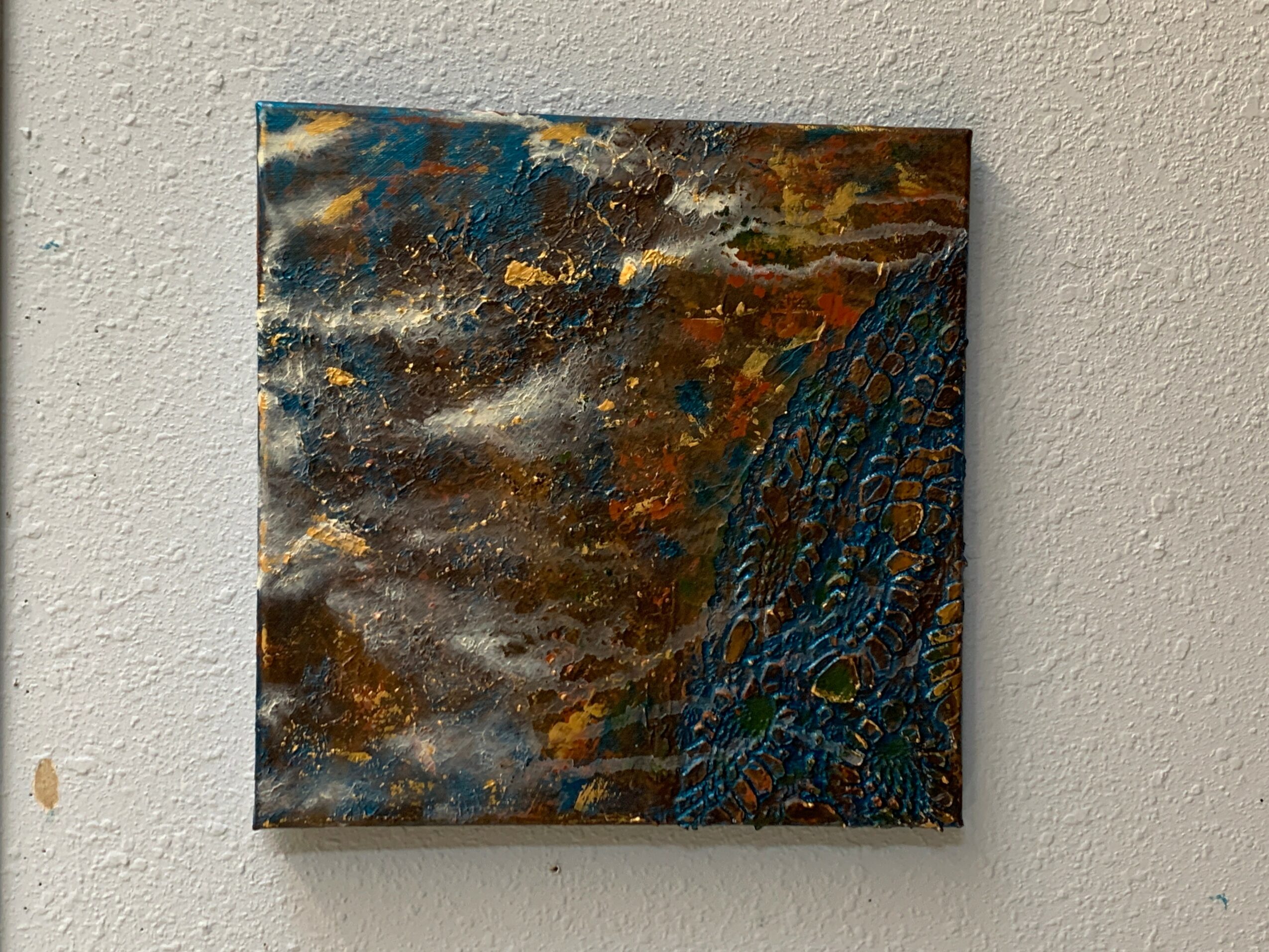 Abstract painting with dark, earthy colors and textured patterns on a wall.