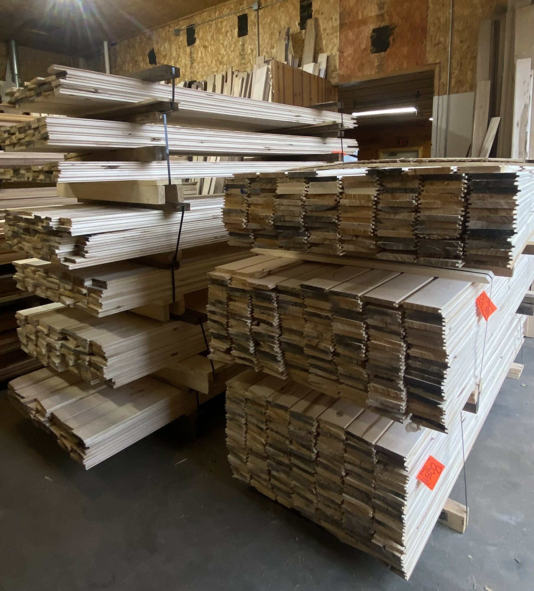 Stacks of white and brown cardboard sheets stored on pallets in a warehouse.