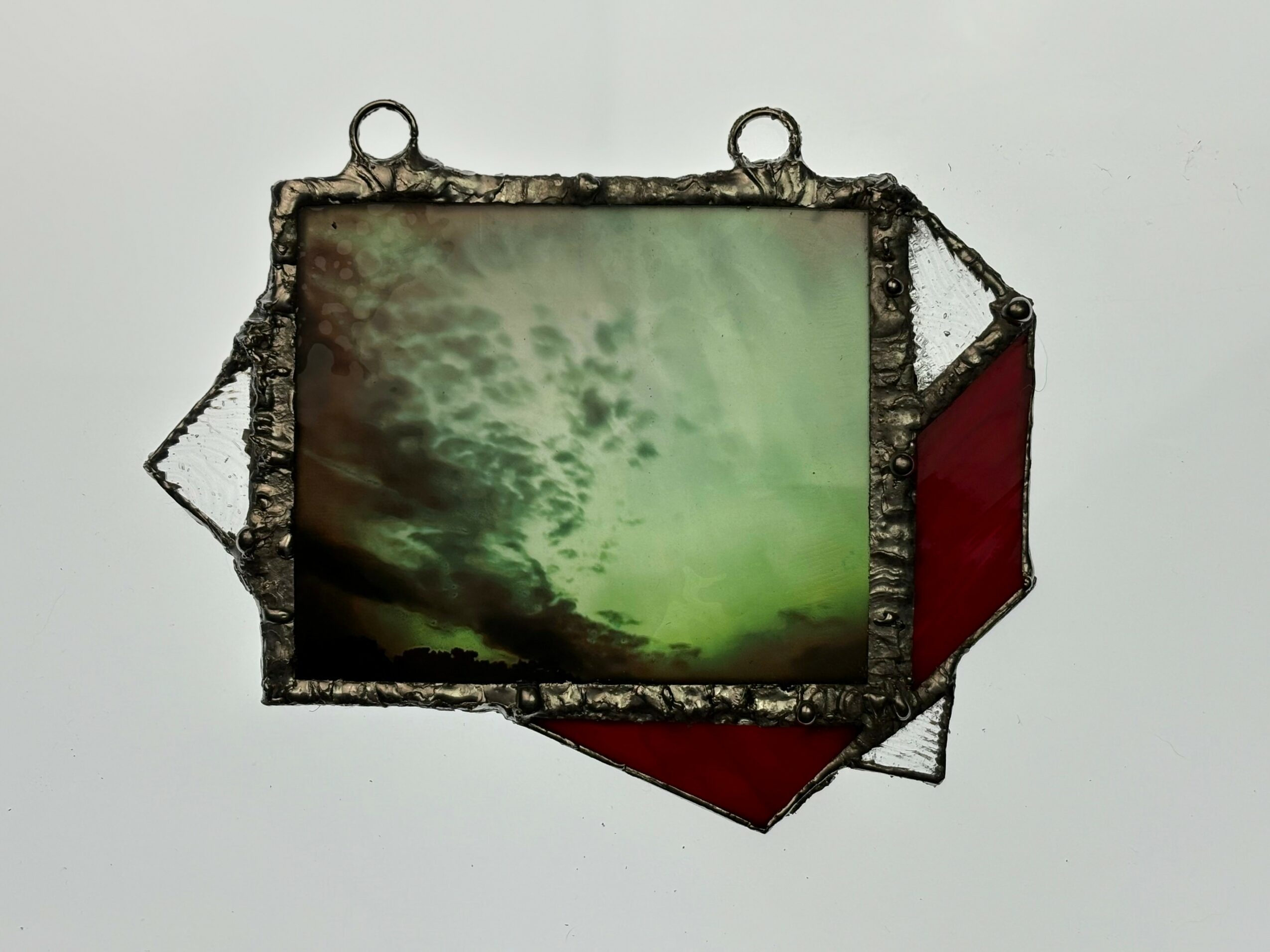 Framed photograph of a cloudy sky with greenish tint, mounted on a white background.