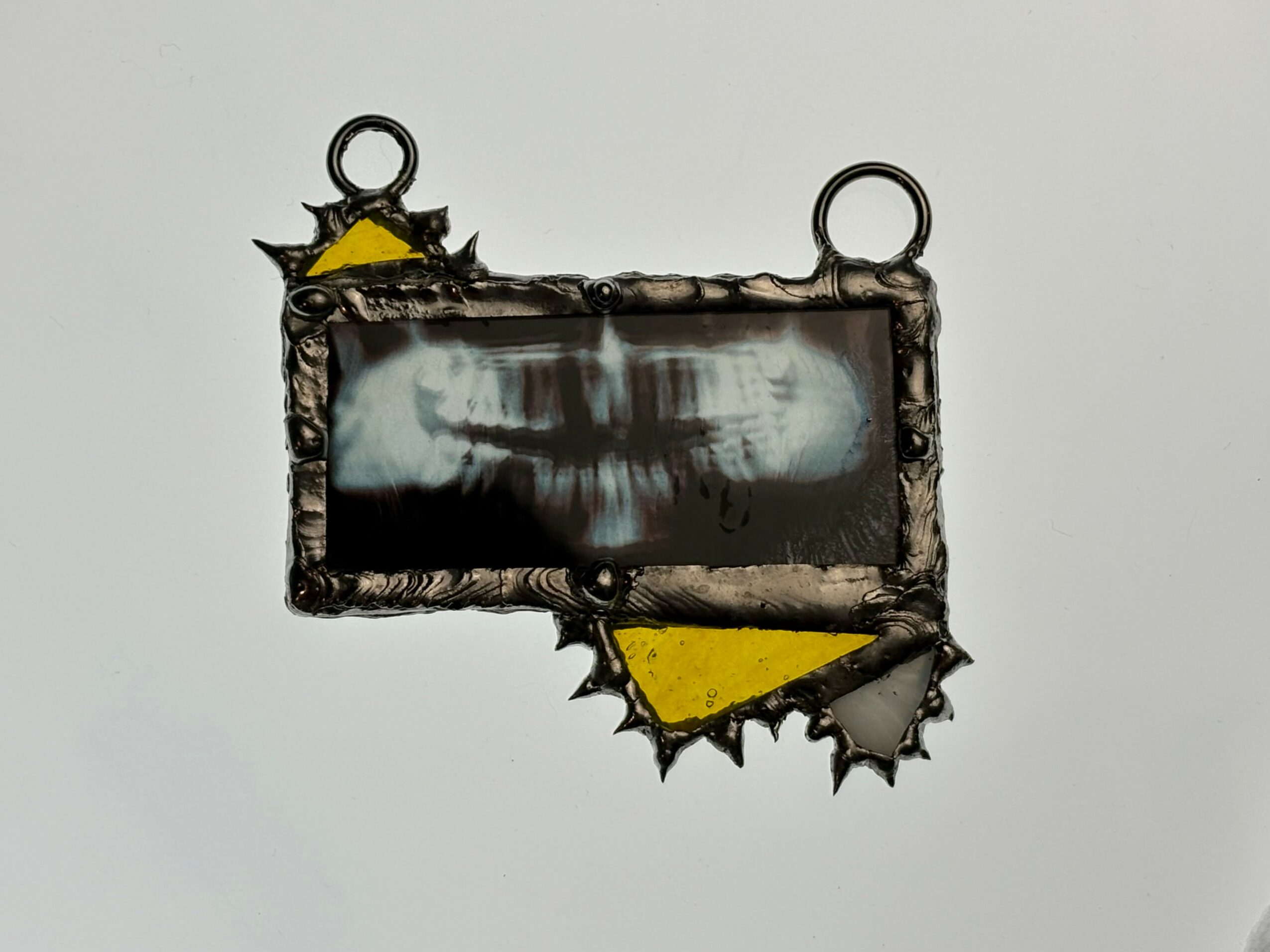 Decorative rectangular frame with jagged edges and yellow accents, hanging against a plain background.