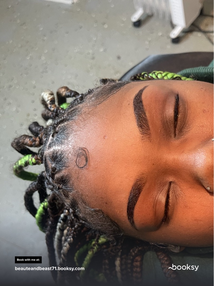 Close-up of a woman with styled braids and closed eyes, lying down on a surface.